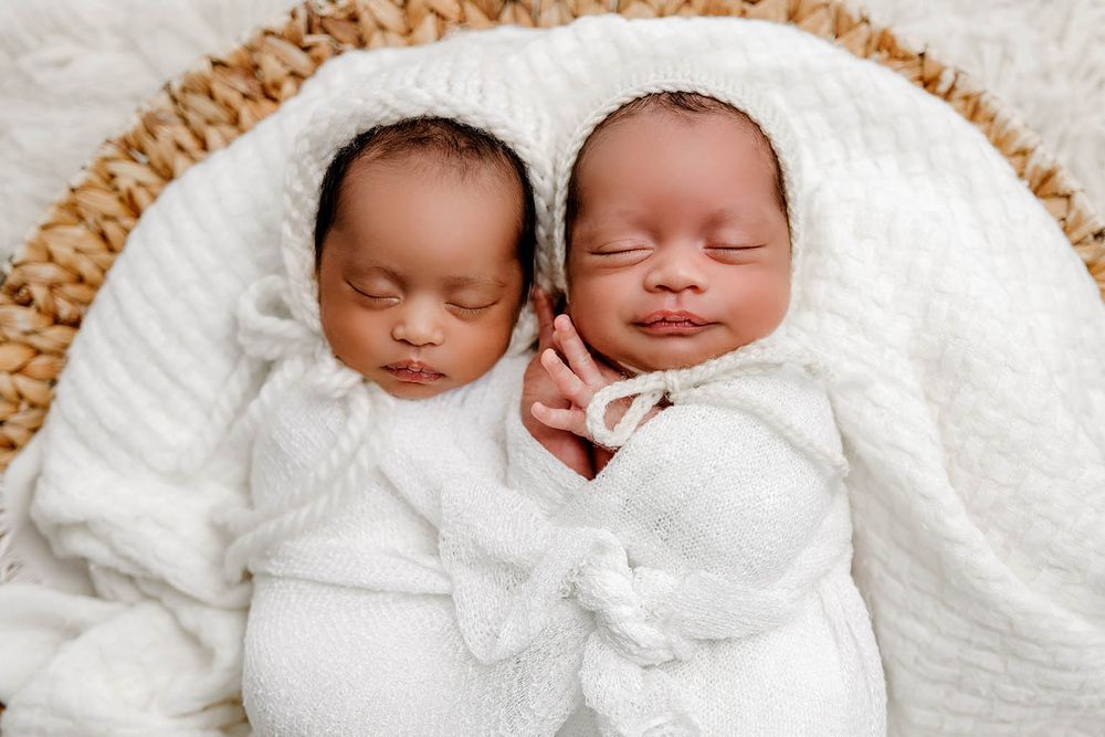 Two newborn twins swaddled in white blankets sleeping peacefully by Temescal Valley twin baby photographer.