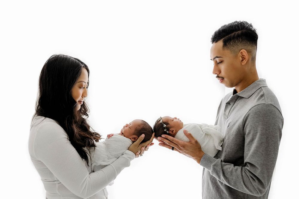A couple tenderly holds their newborn twins facing each other by Temescal Valley twin baby photographer.