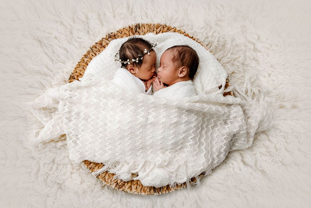Two newborn twins sleeping peacefully in a wicker basket by Temescal Valley twin baby photographer.