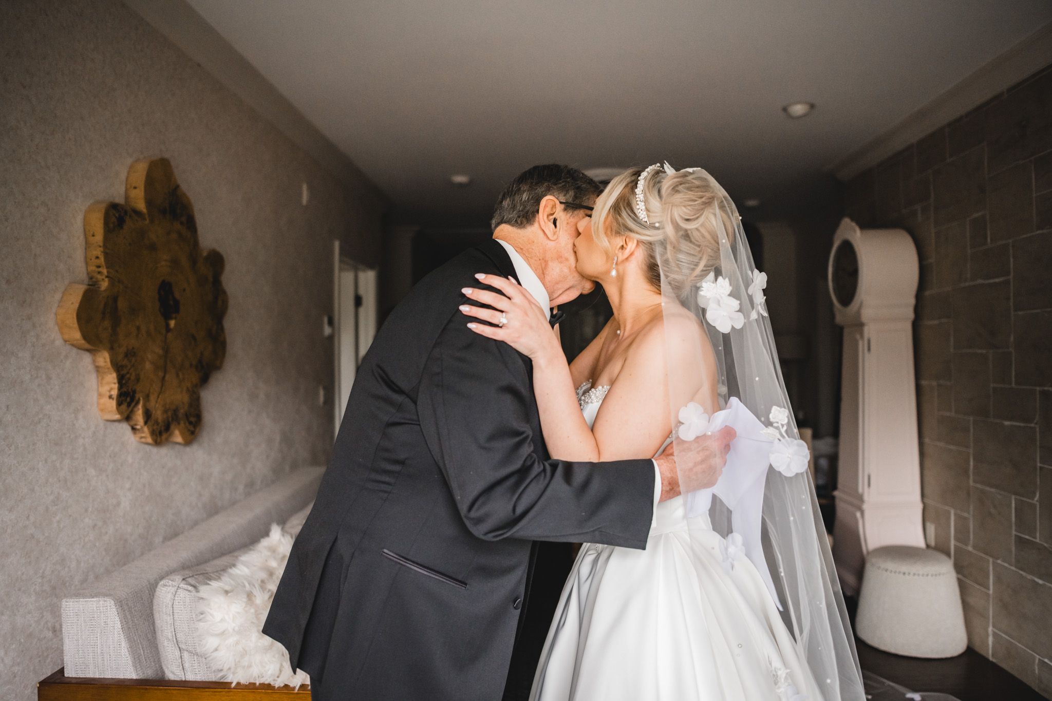 Bride and groom sharing emotional first look kiss in hotel suite before wedding ceremony.