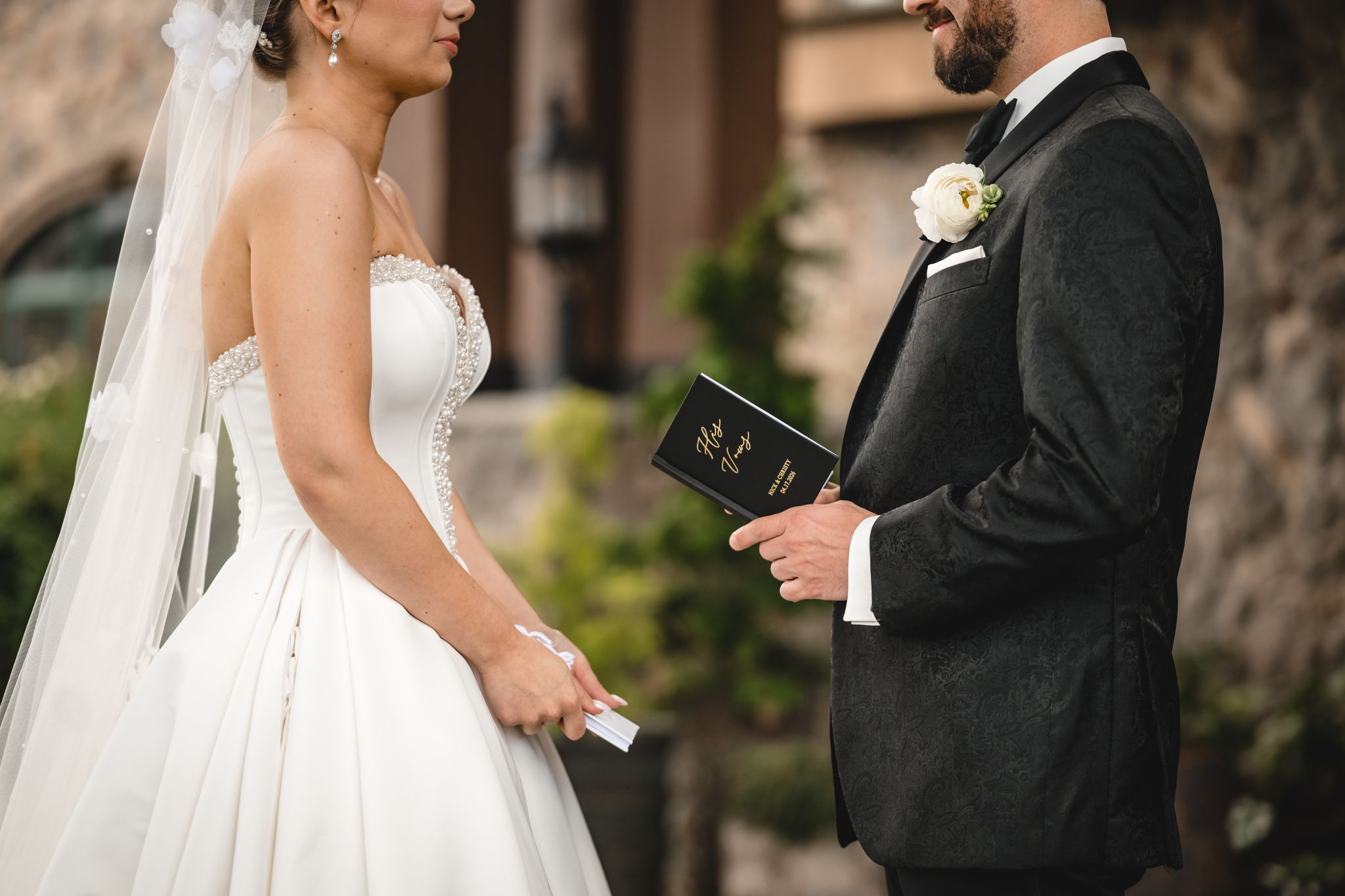A bride and groom exchange vows outdoors, with the groom holding a Bible during the ceremony.