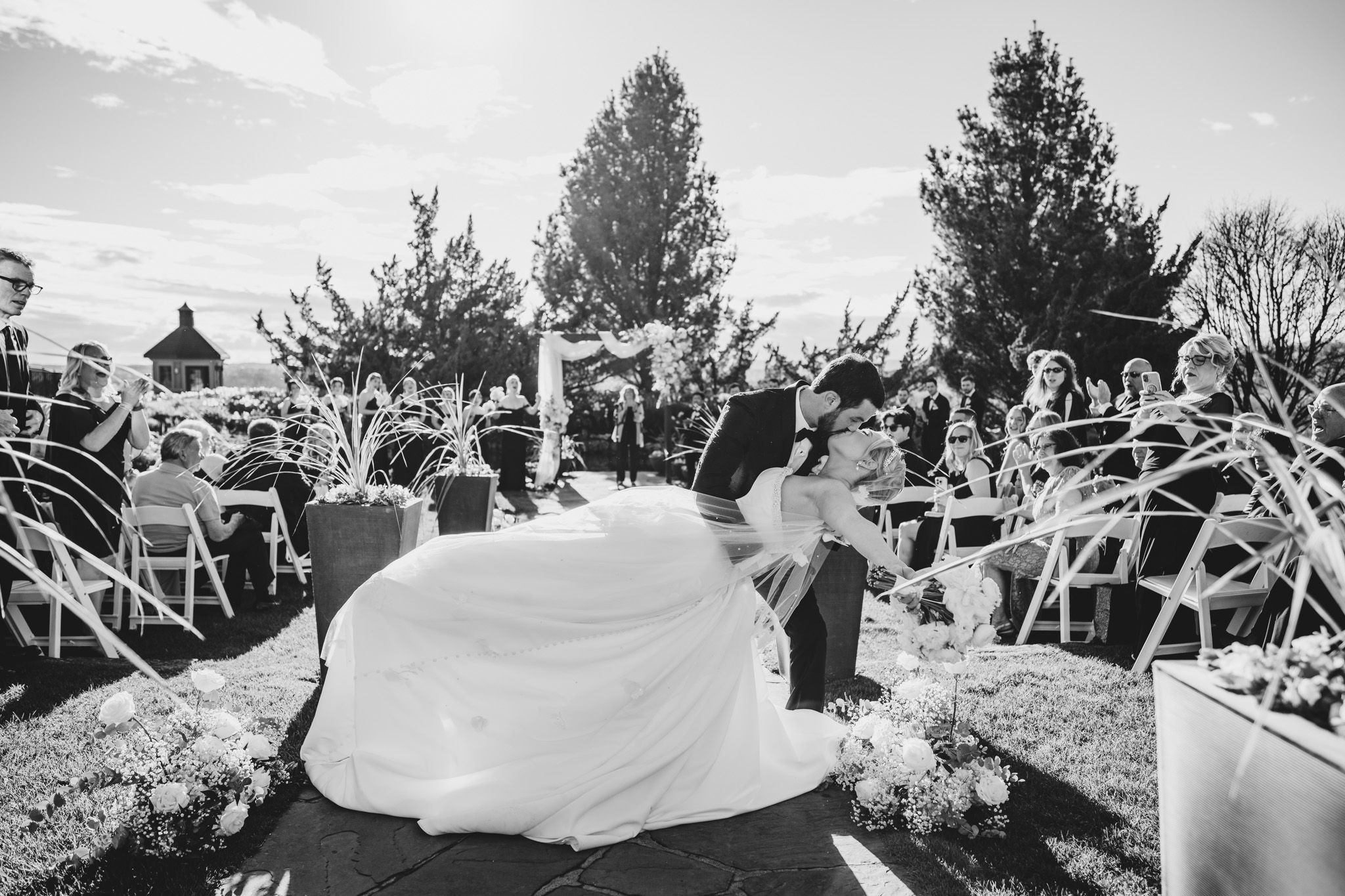 Bride and groom sharing a dramatic dip kiss at the altar during their outdoor wedding ceremony.