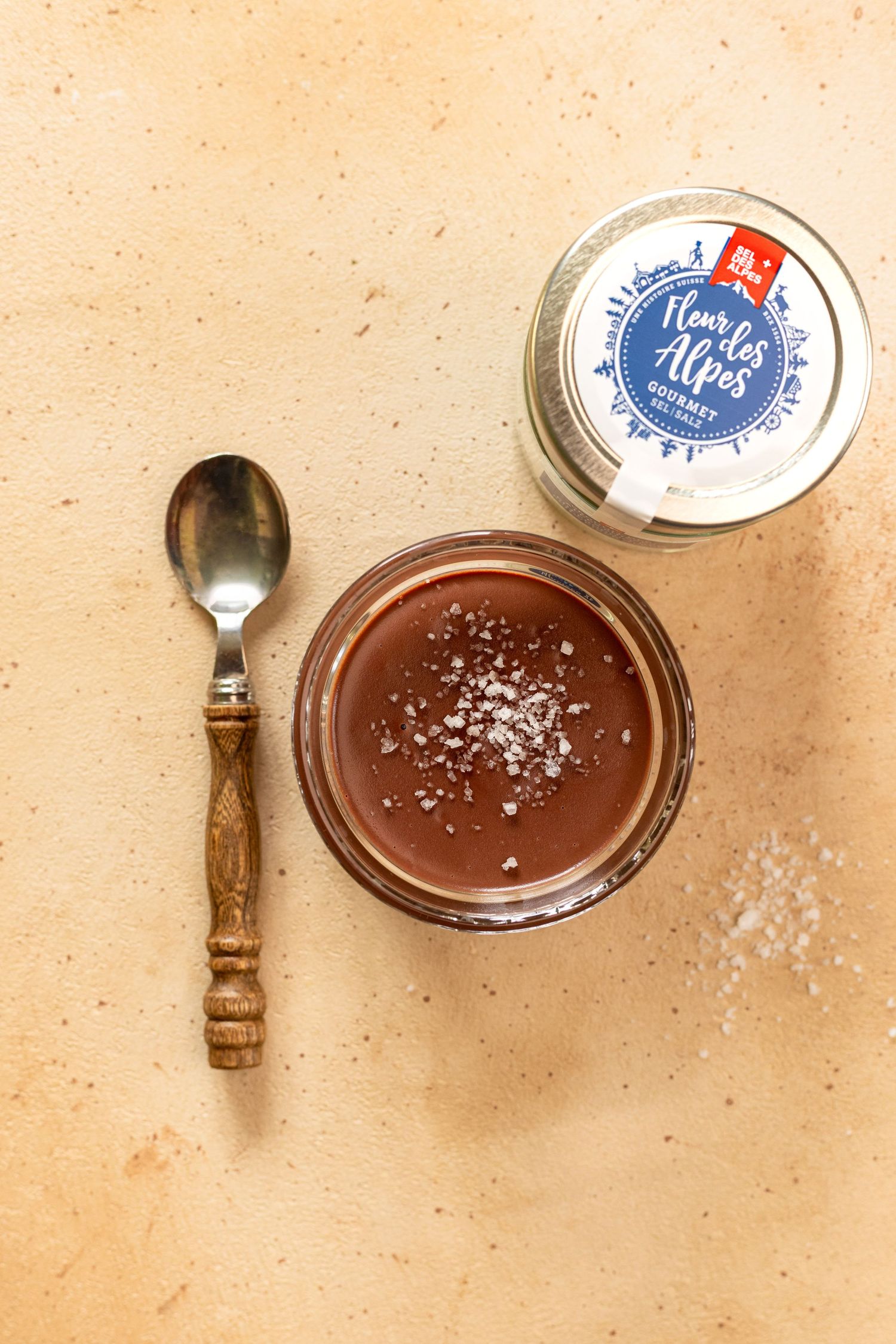 A spoon scoops creamy chocolate mousse from a glass bowl showing its smooth and airy texture.