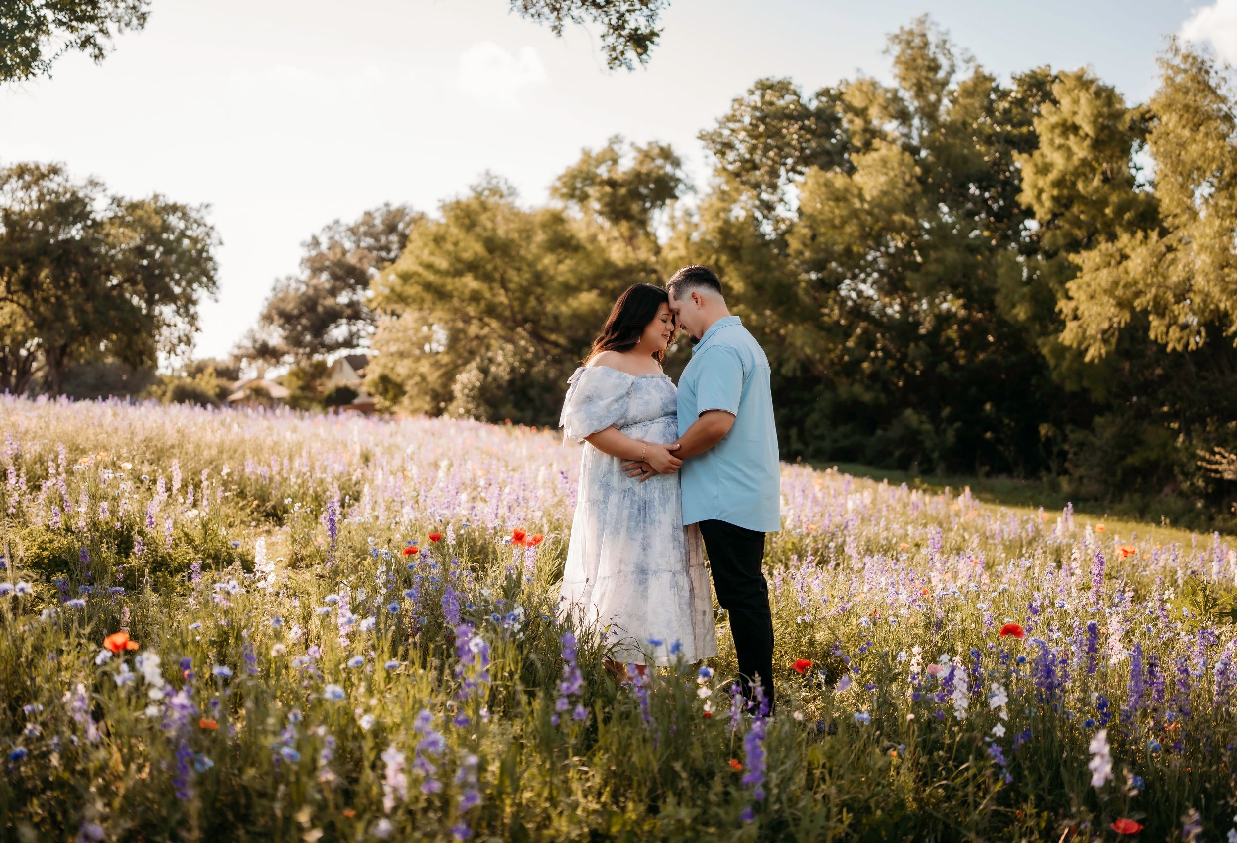 Couple sharing a tender moment in a vibrant wildflower field with bluebonnets and poppies during golden hour.