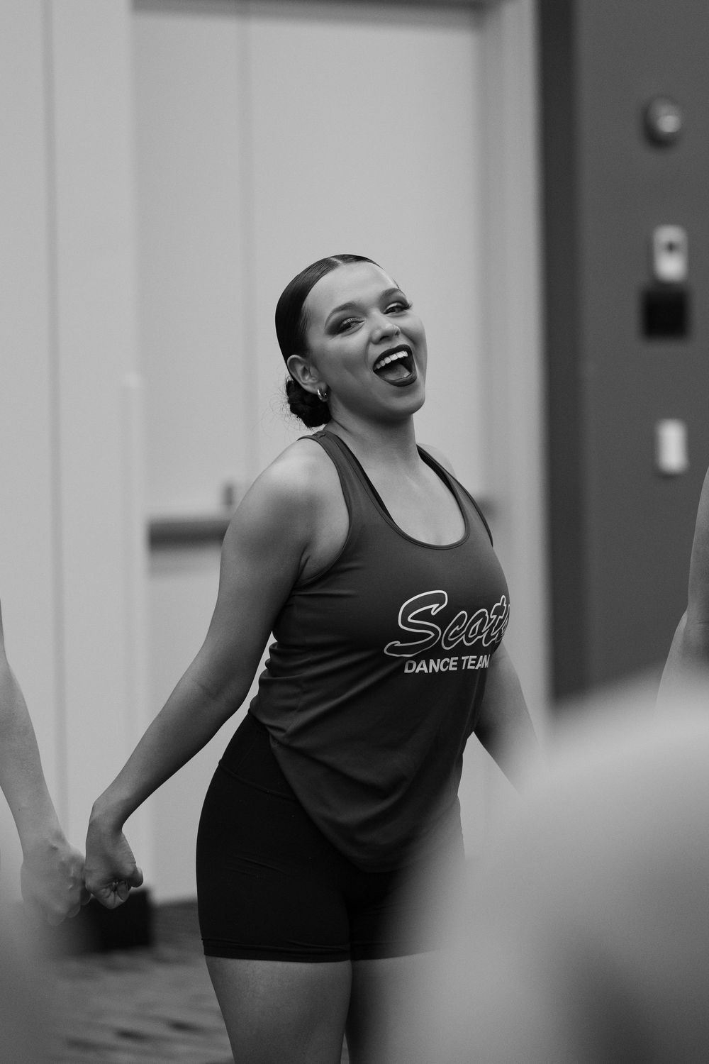 Smiling young woman in a Scott Dance Team tank top performing at a dance event in black and white photo.