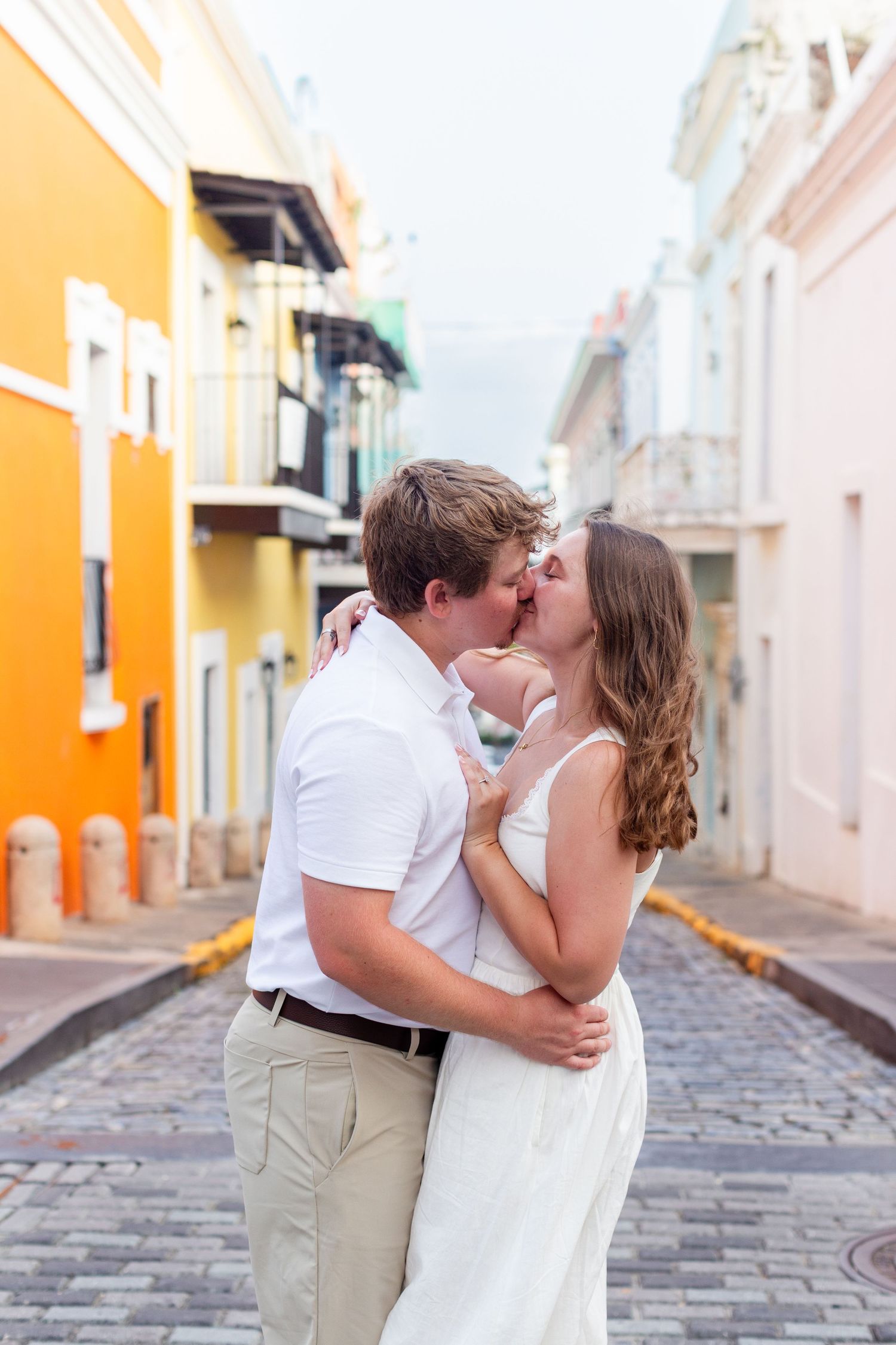 Couples portrait kissing in the middle of the street. Engagement photo session in Old San Juan, Puerto Rico.