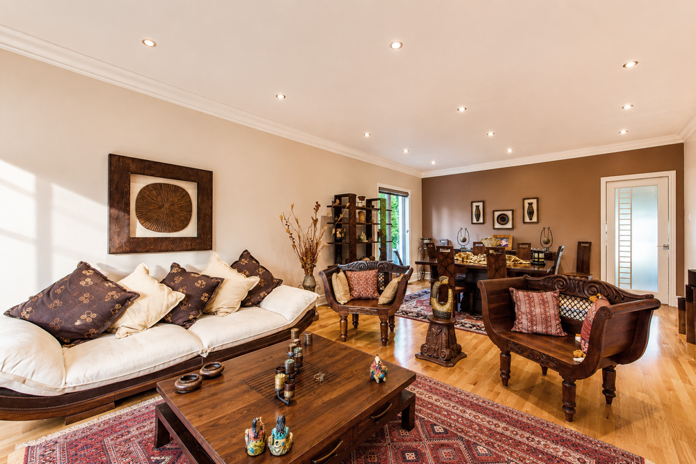 Elegant living room with white sofa, Persian rug, wooden furniture, and warm recessed lighting in a neutral-toned space.