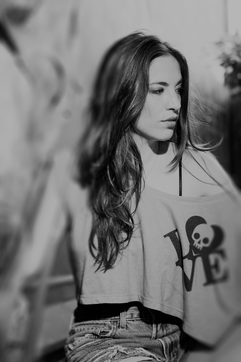 Black and white portrait of a young brunette woman wearing a LOVE skull graphic t-shirt.