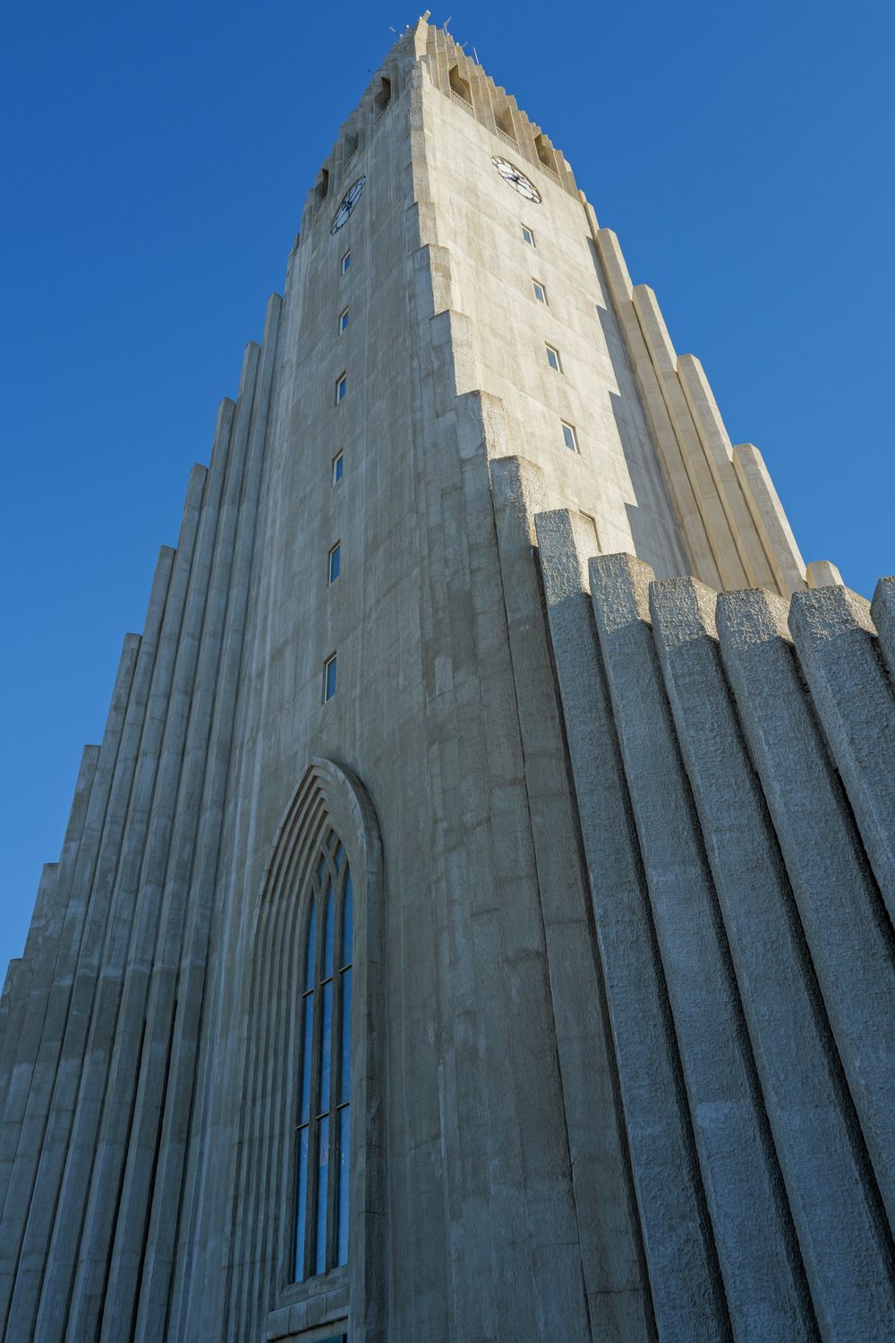 Towering Hallgrimskirkja church facade in Reykjavik showcasing dramatic angular architecture against blue sky.