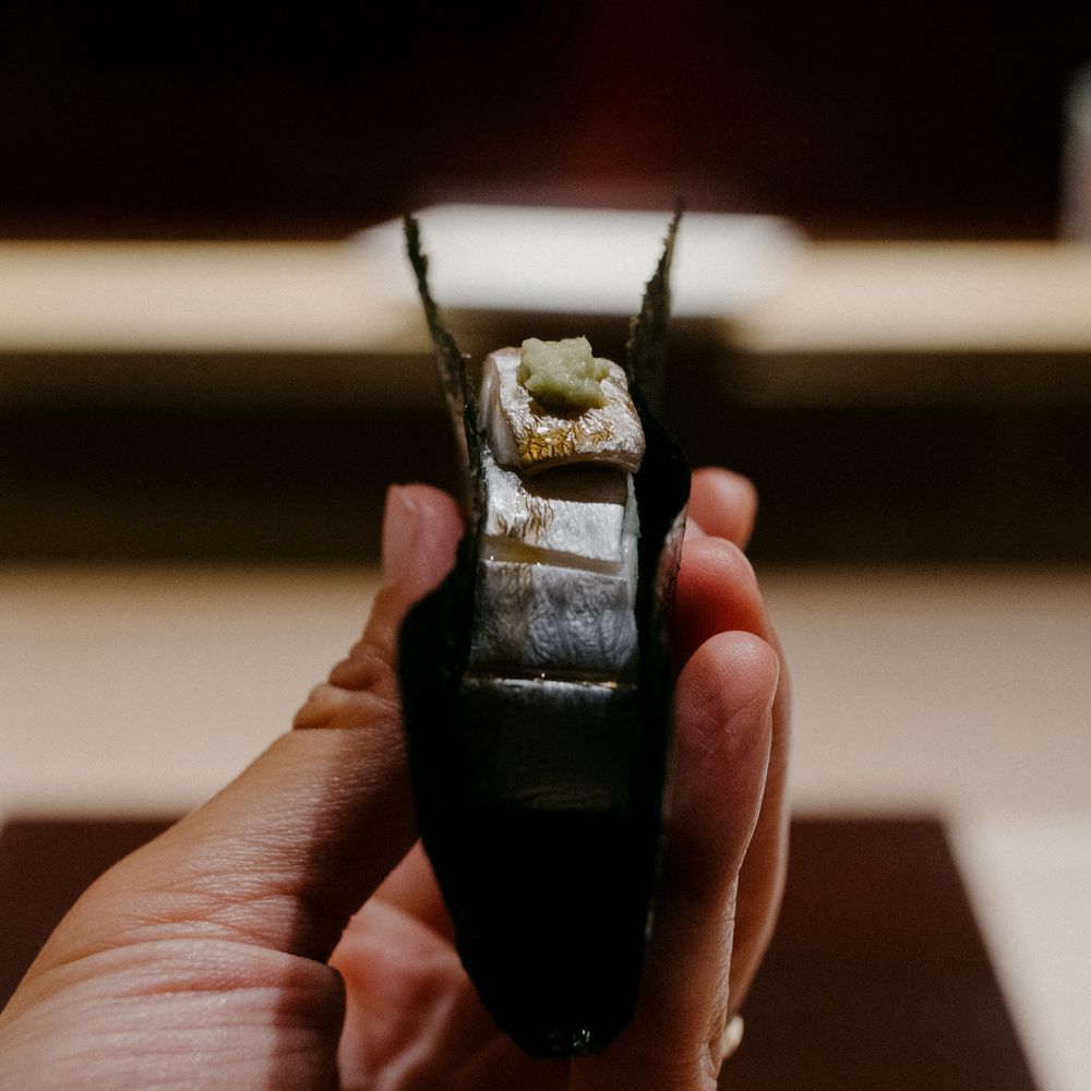 Close-up shot of a perfectly rolled piece of sushi held between fingers.