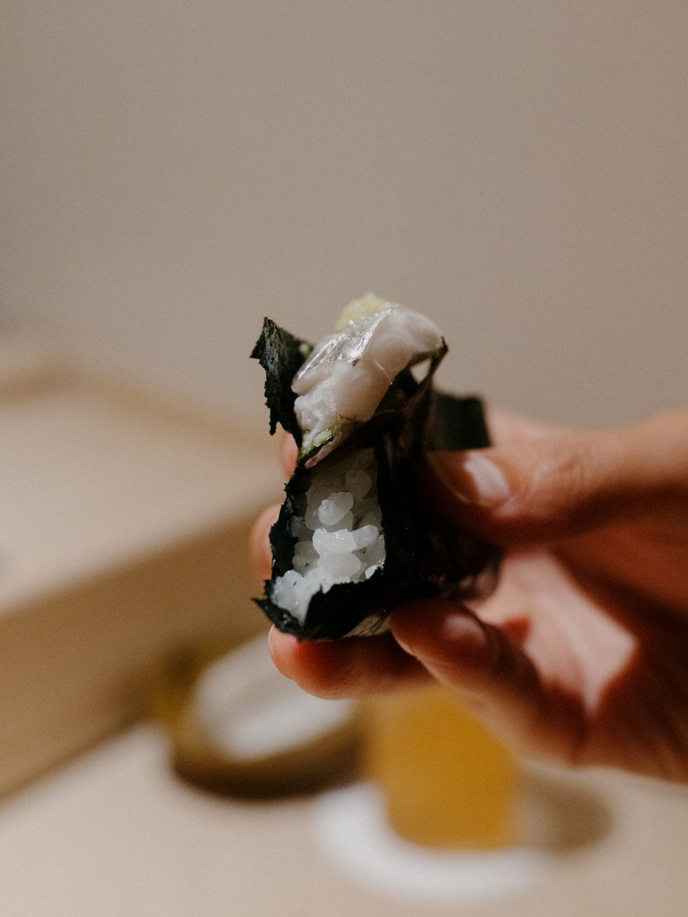 Hand holding a piece of nori-wrapped sushi showing the layered ingredients.