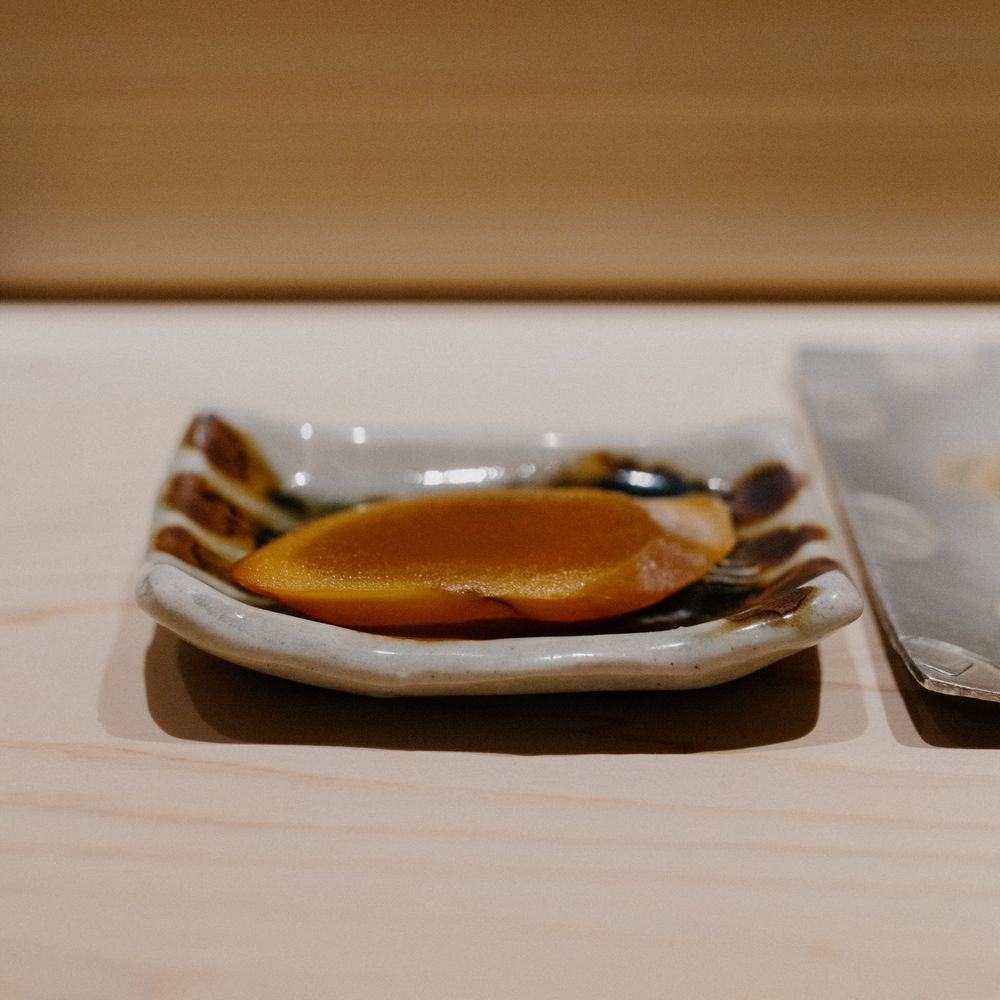 An amber-colored sauce or reduction served on an elegant white ceramic plate.
