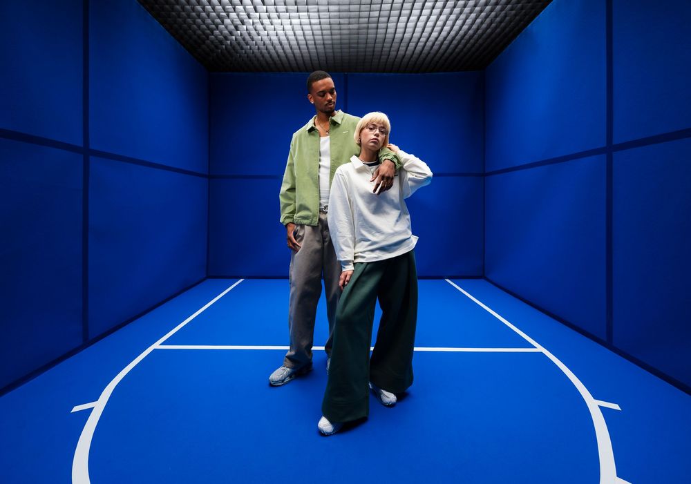 Streetwear fashion photo of two people posing together in a blue indoor court or studio room
