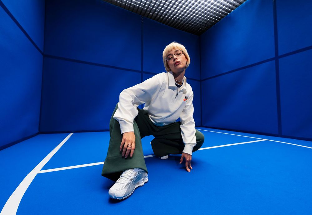 Sneaker and streetwear photo of a person crouching on a vibrant blue indoor court setting