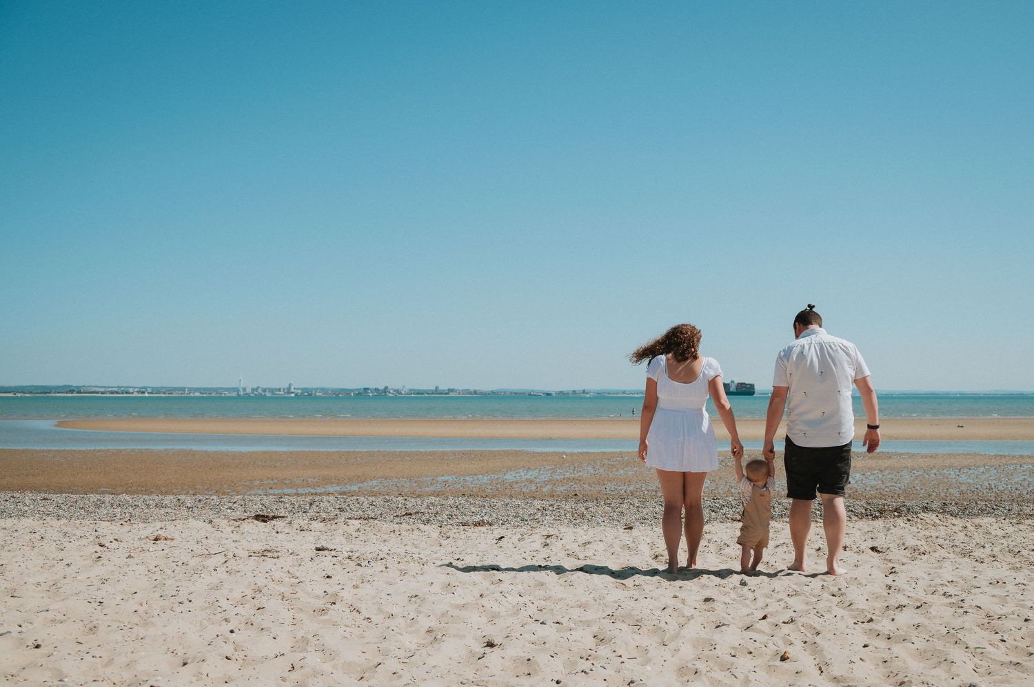 Family splashing and playing together in ocean waves at the beach.