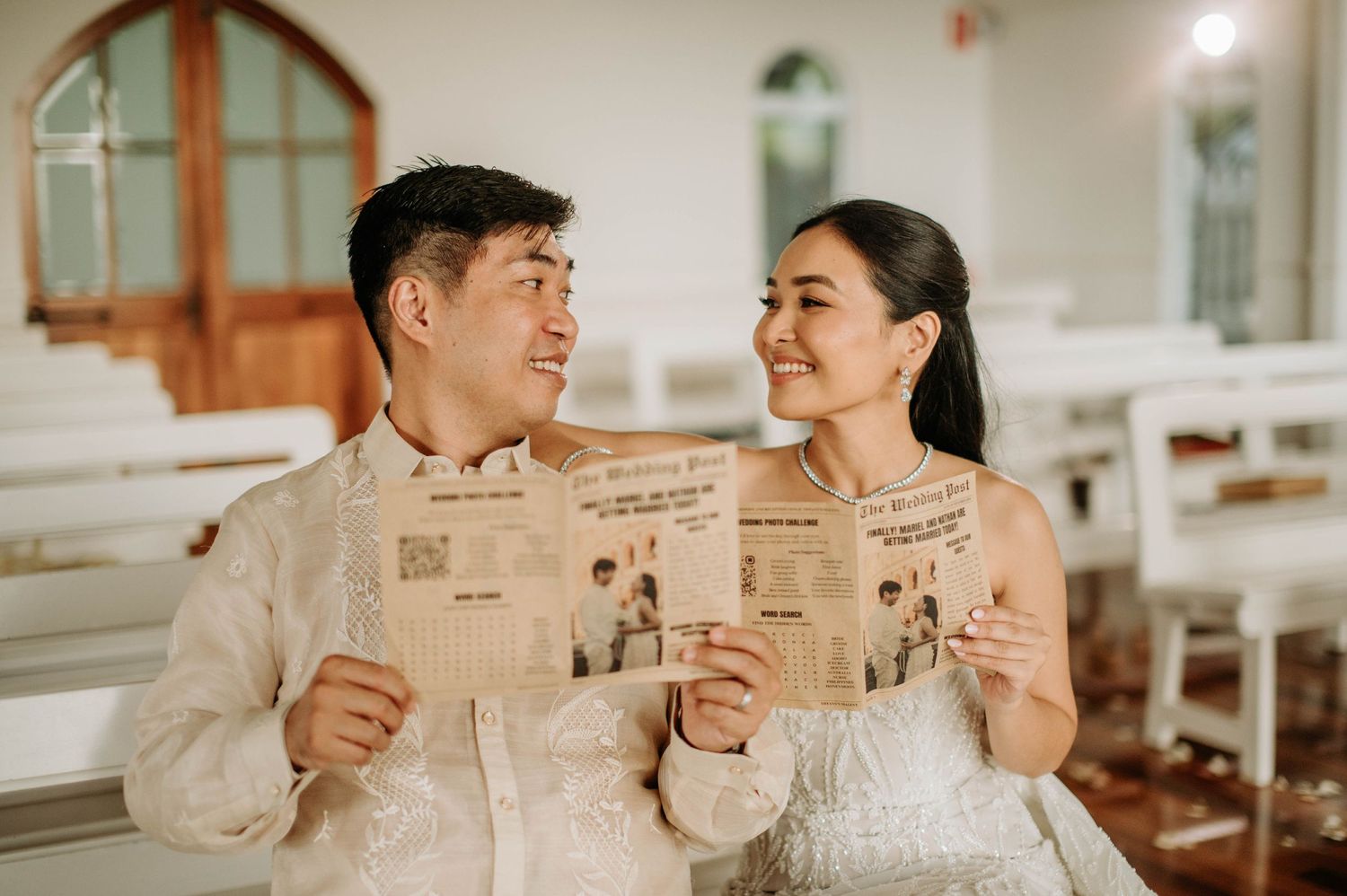 Couple reading newspapers together in white chapel setting.