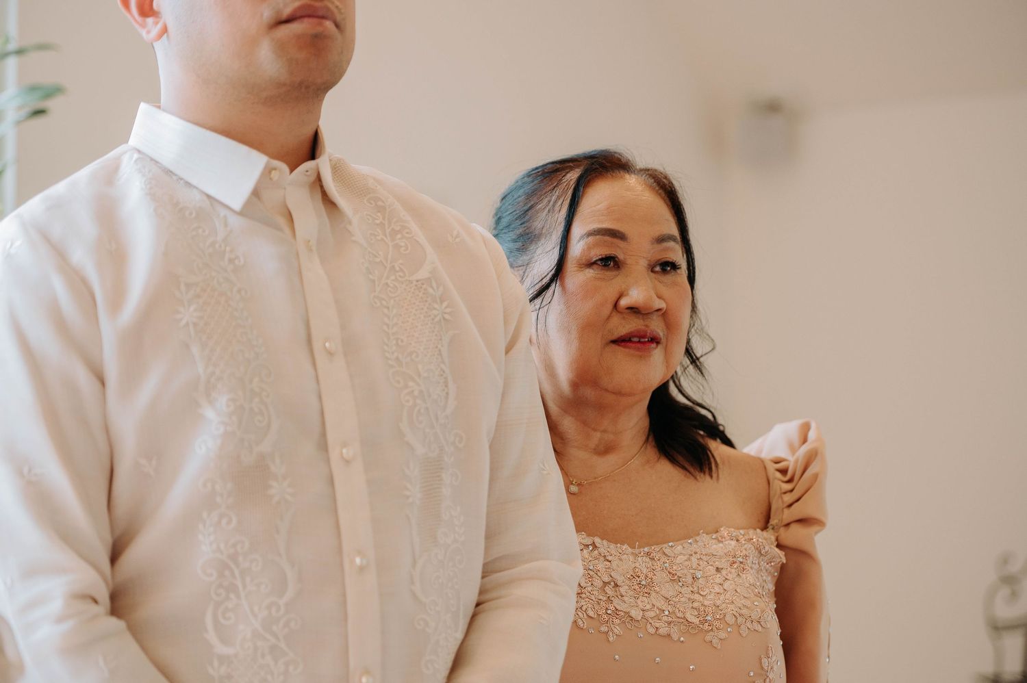 Wedding party members in formal white and pink attire pose together.