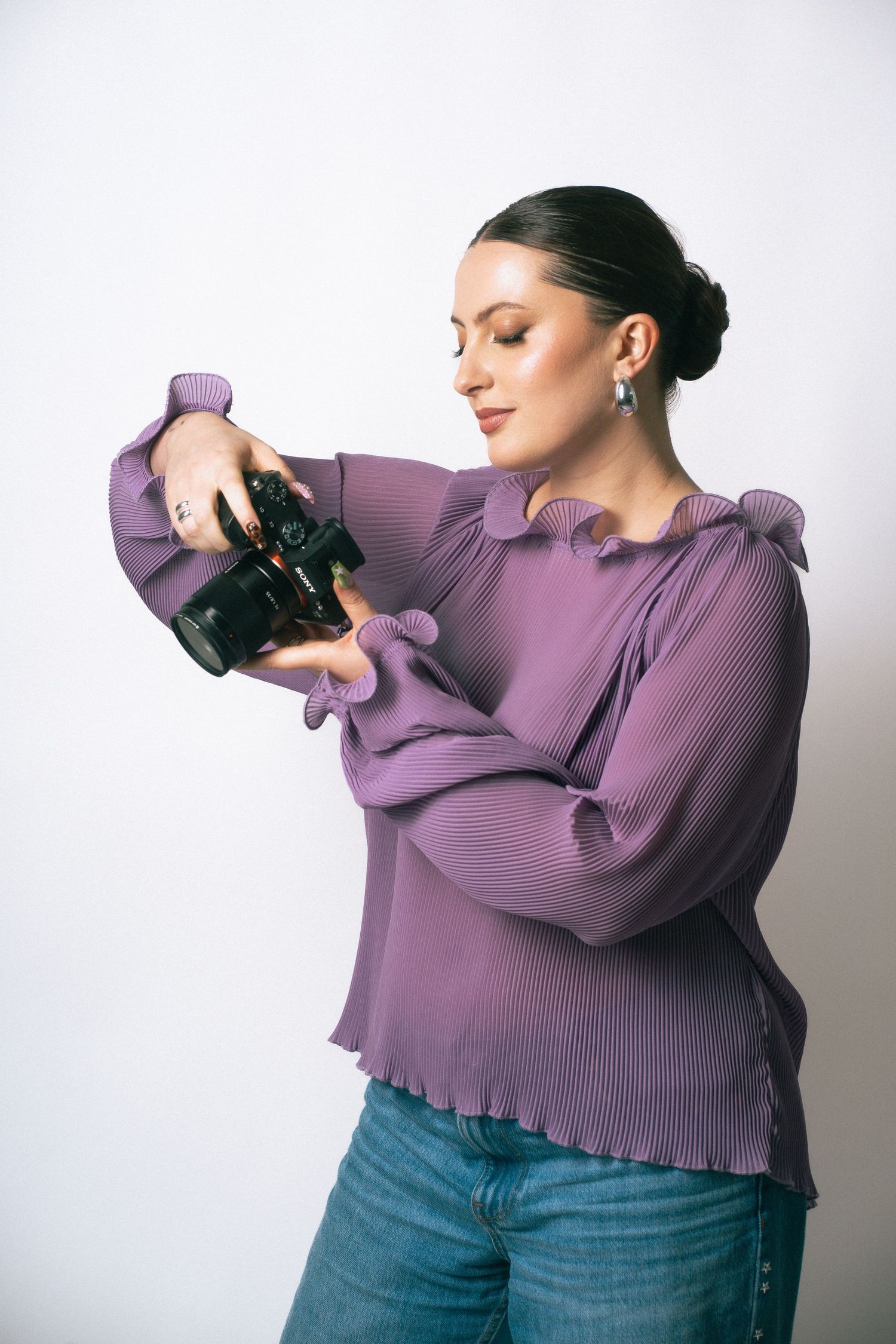 Professional photographer with red hair using a DSLR camera against white background.