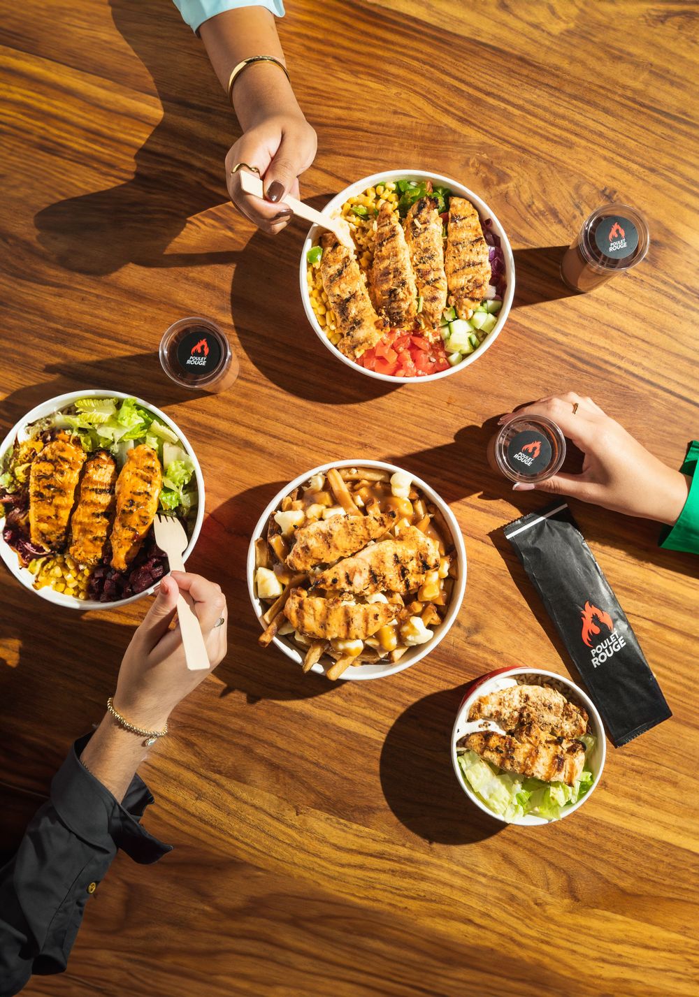 Overhead view of multiple rice bowls with grilled chicken and drinks on a wooden table. Mtlshutter photography