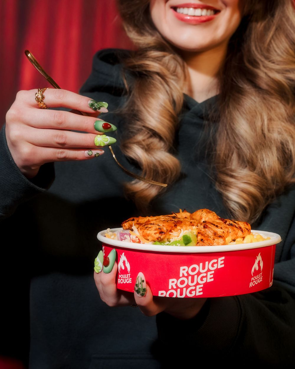 A person holds a steaming bowl of pasta from Rouge Rouge Rouge restaurant with perfectly manicured nails.