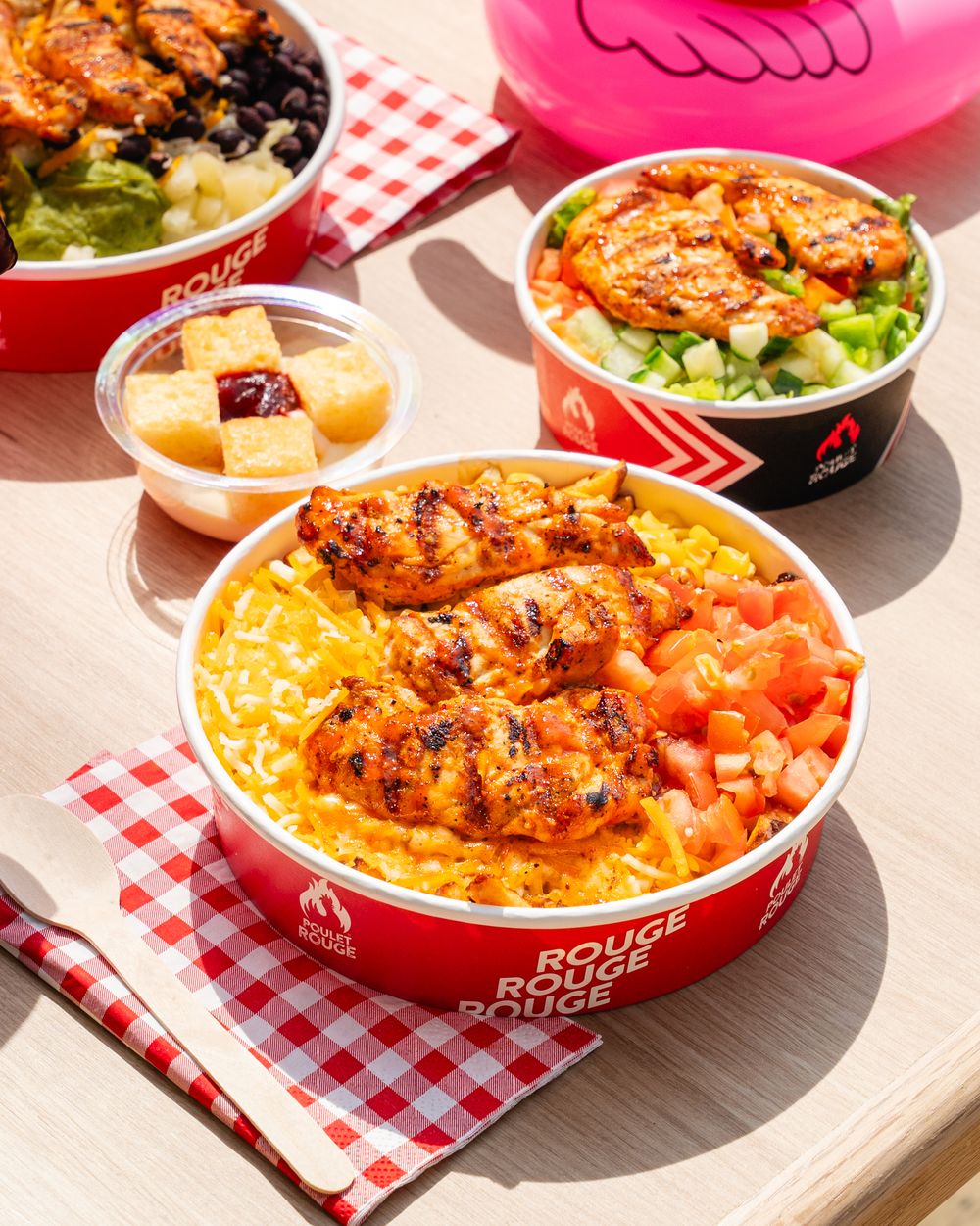 Rouge Rouge restaurant bowls with grilled chicken, yellow rice, tomatoes, and fresh salad served in branded red containers.