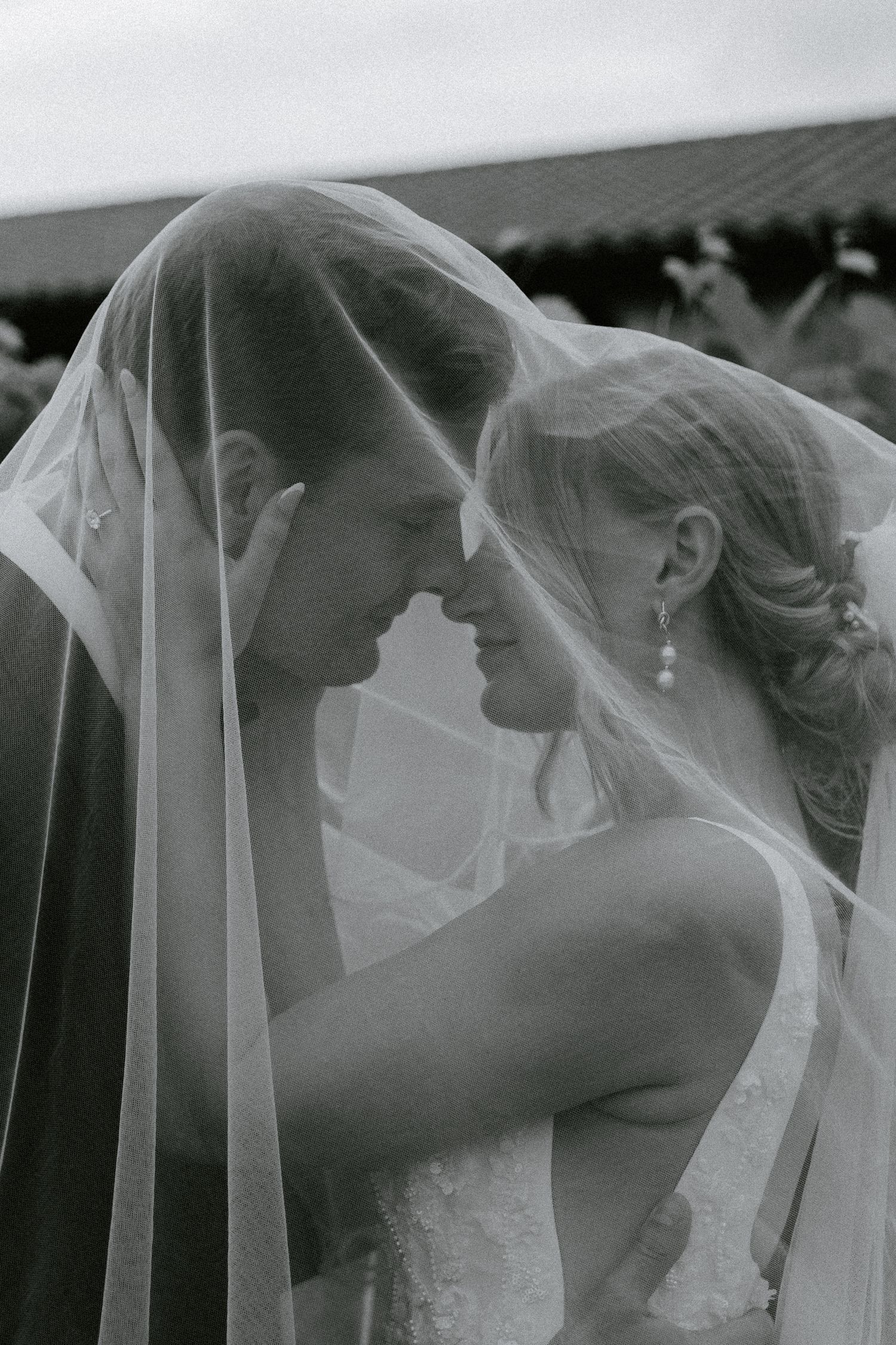 Romantic black and white wedding portrait under a flowing veil in a European-inspired vineyard.