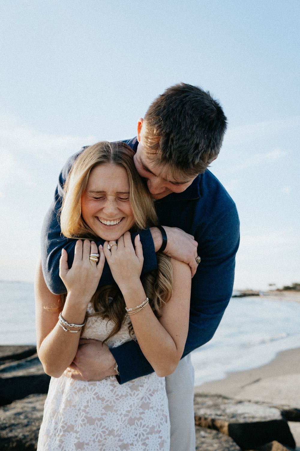 A romantic couple shares intimate moments on the beach as they embrace and laugh together in a series of candid photos.