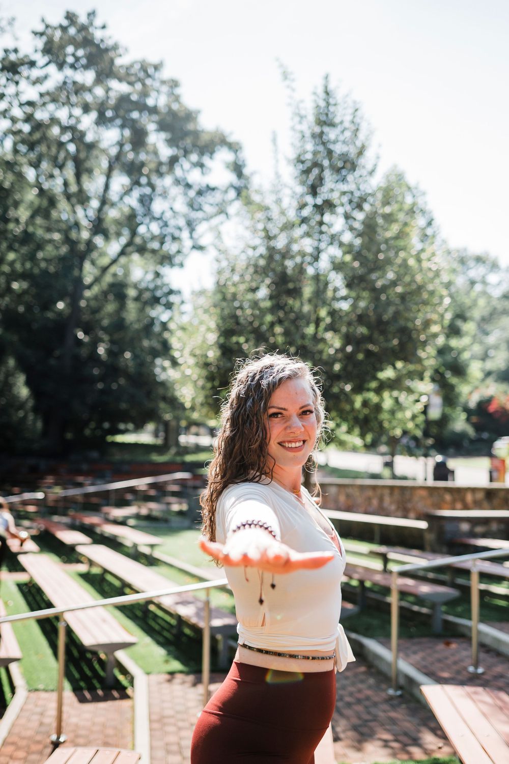 A rustic outdoor wedding venue with wooden benches arranged in rows under tall trees.
