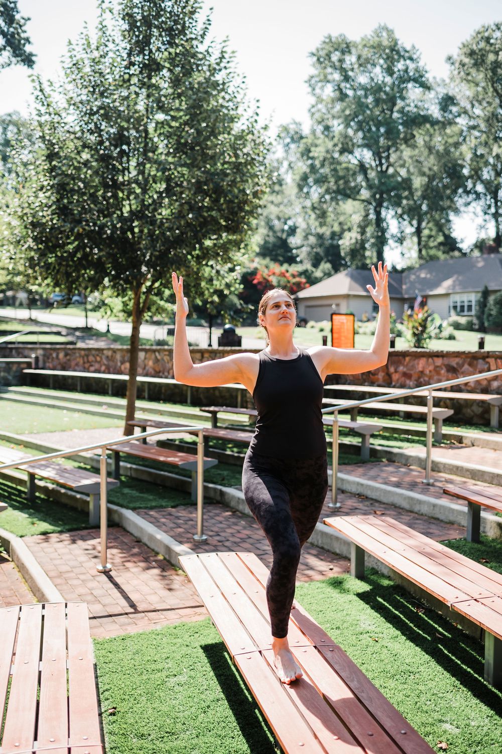 Person in black outfit poses on wooden bleachers in outdoor park setting.