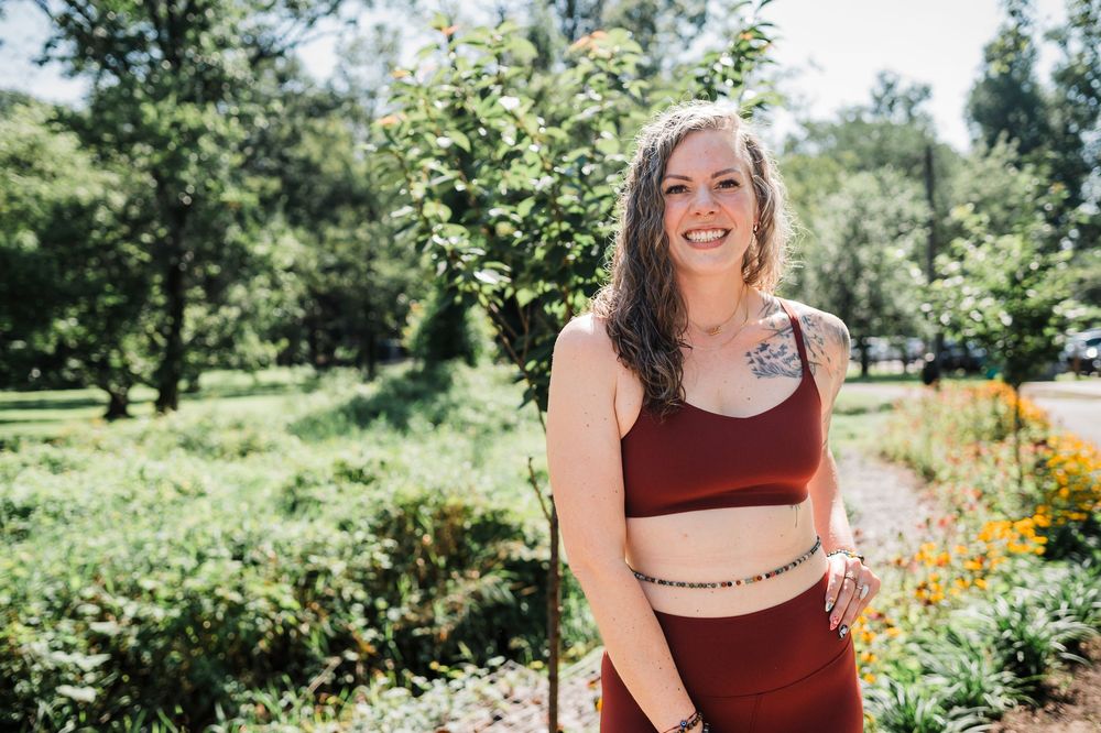 A person joyfully explores a sunny summer garden filled with vibrant flowers and lush greenery.