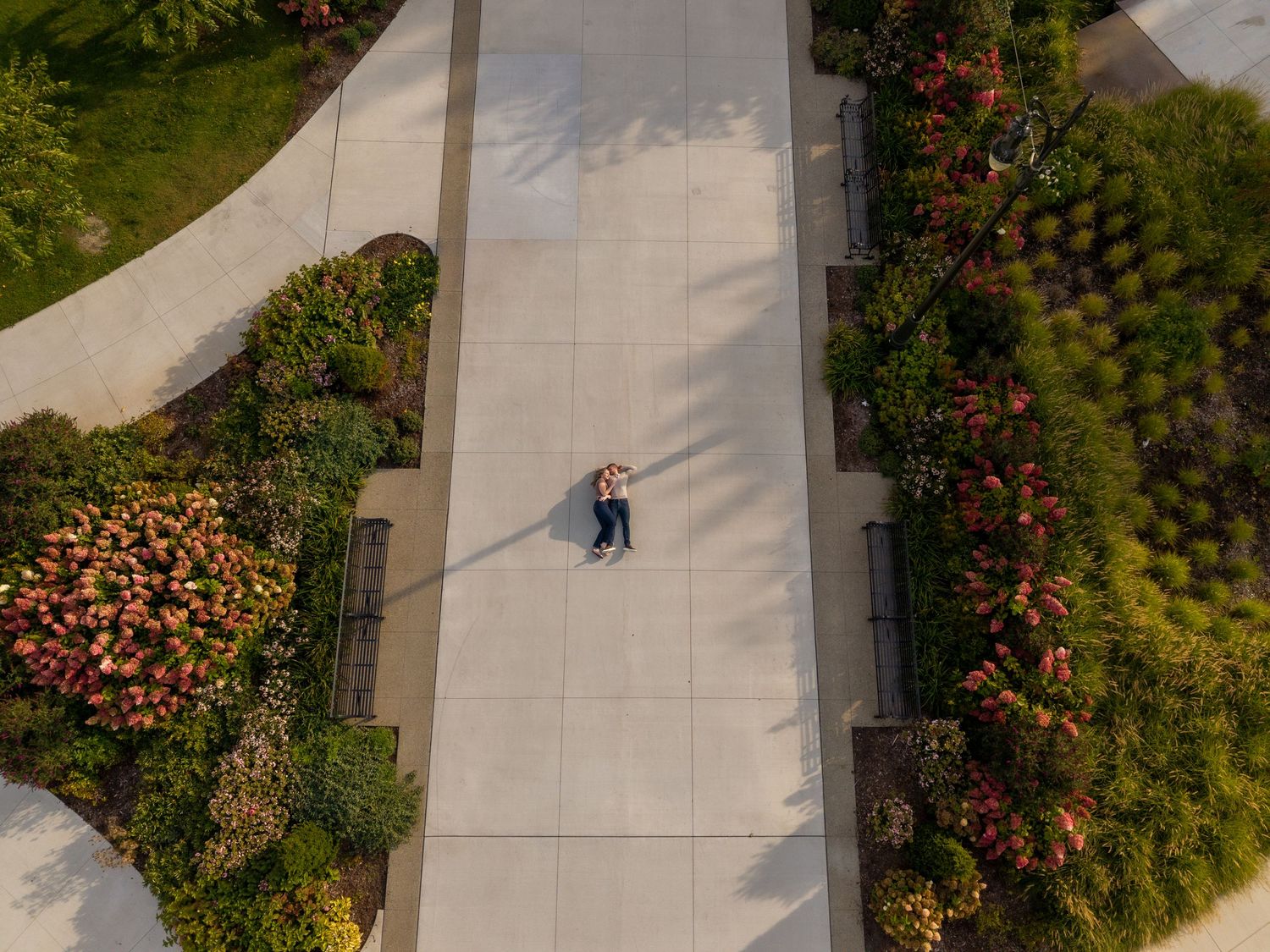 drone shot of couple during engagement shoot laying on the ground, in Rosevelt park in front of michigan central station