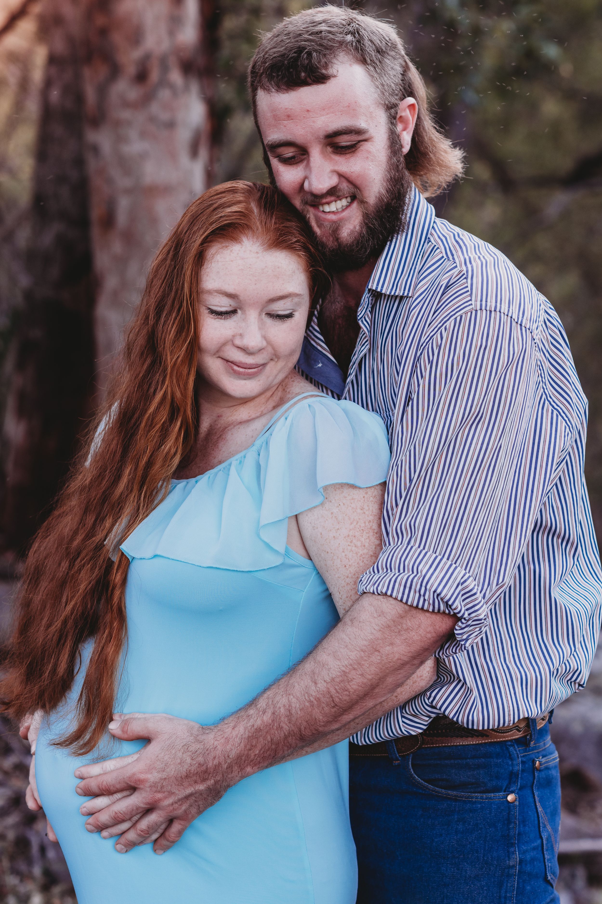 A tender maternity portrait showing a couple embracing outdoors.