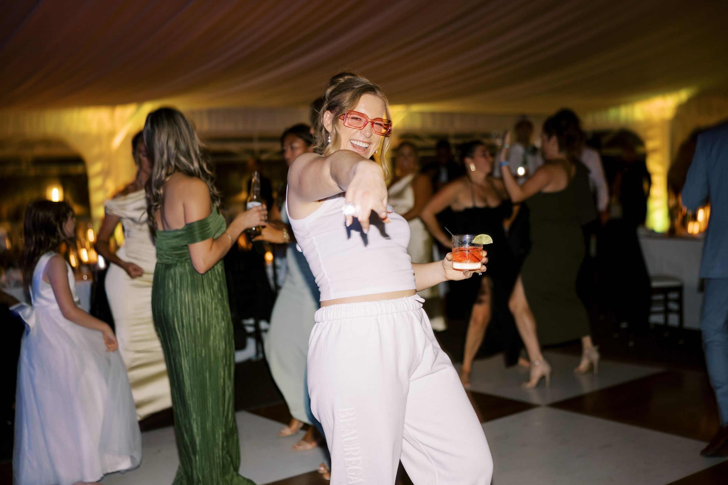 Wedding guests dancing together on a dimly lit ballroom dance floor during an evening reception celebration.