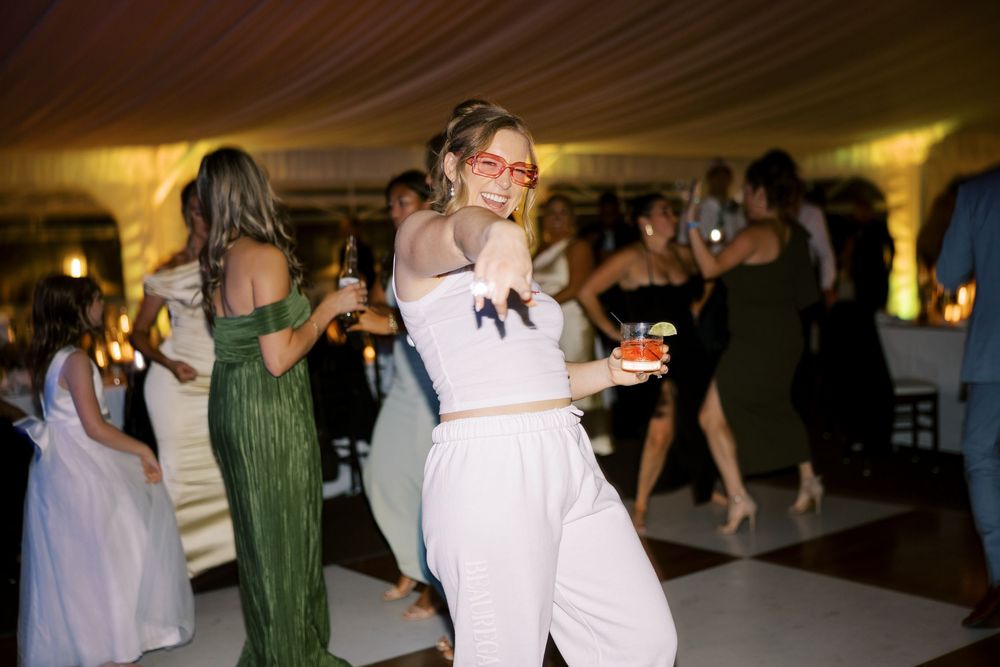 Wedding guests dancing together on a dimly lit ballroom dance floor during an evening reception celebration.
