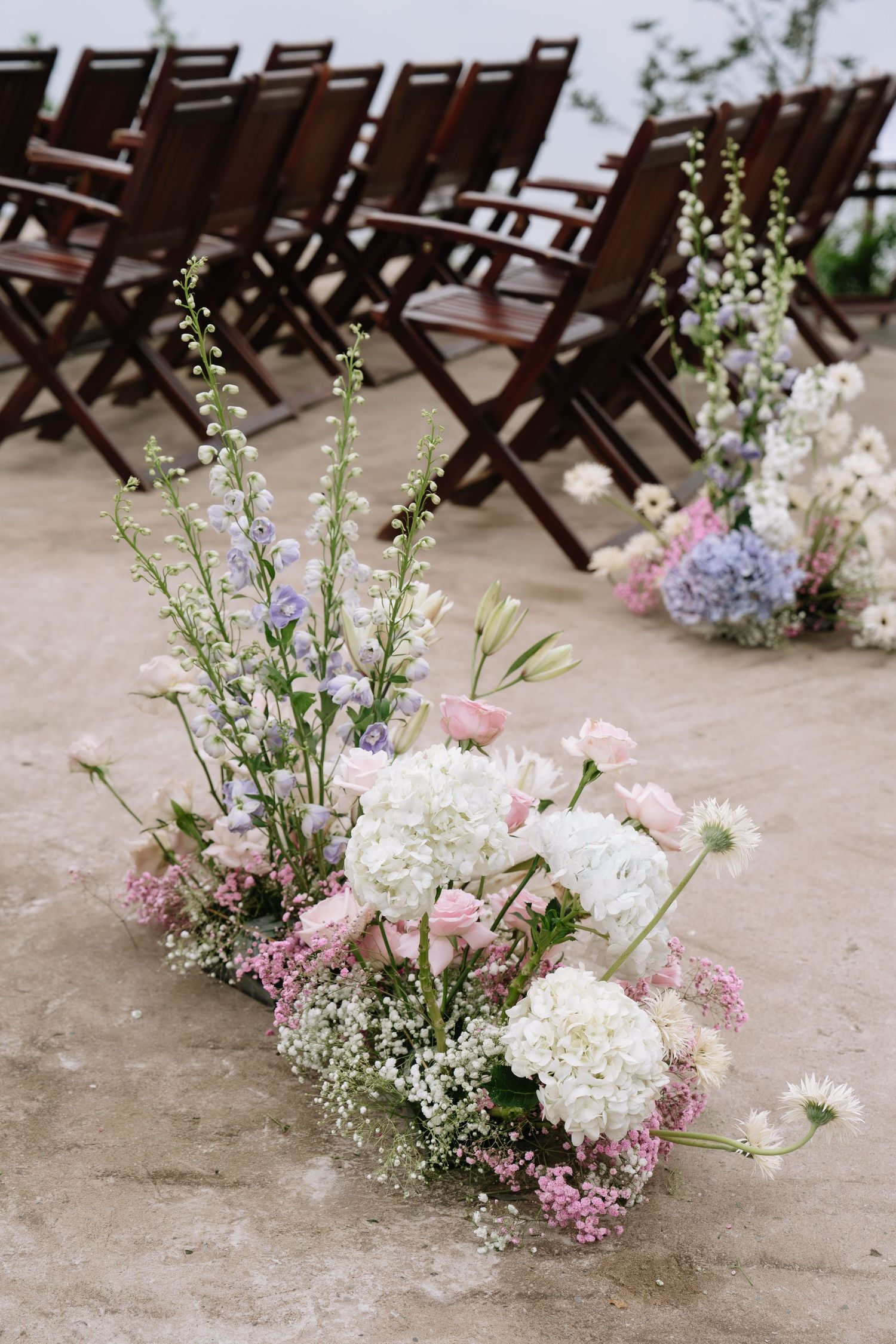 Elegant pink, white, and lavender floral aisle arrangements at an outdoor wedding ceremony venue.