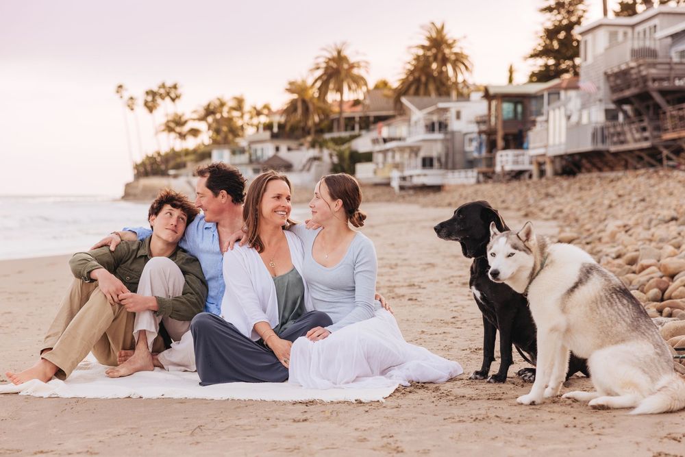 Happy couple and their dog enjoying a romantic sunset photoshoot at a scenic beach setting.