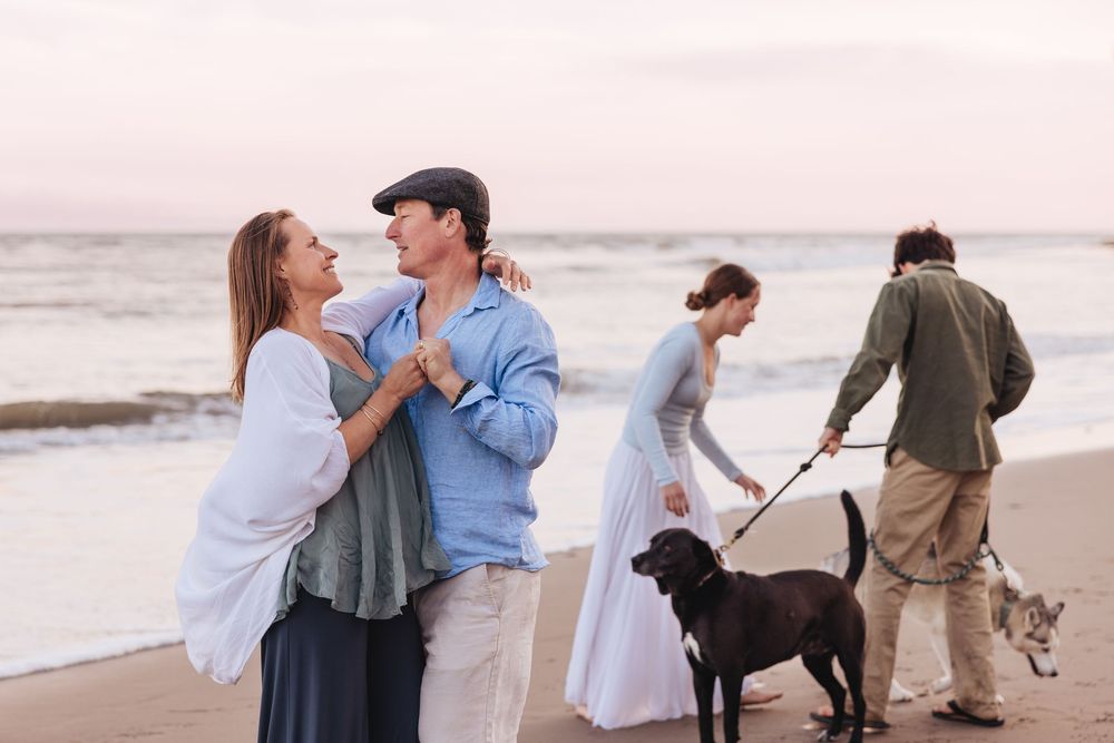 Romantic beach photos of couples walking and embracing along the shoreline at sunset.