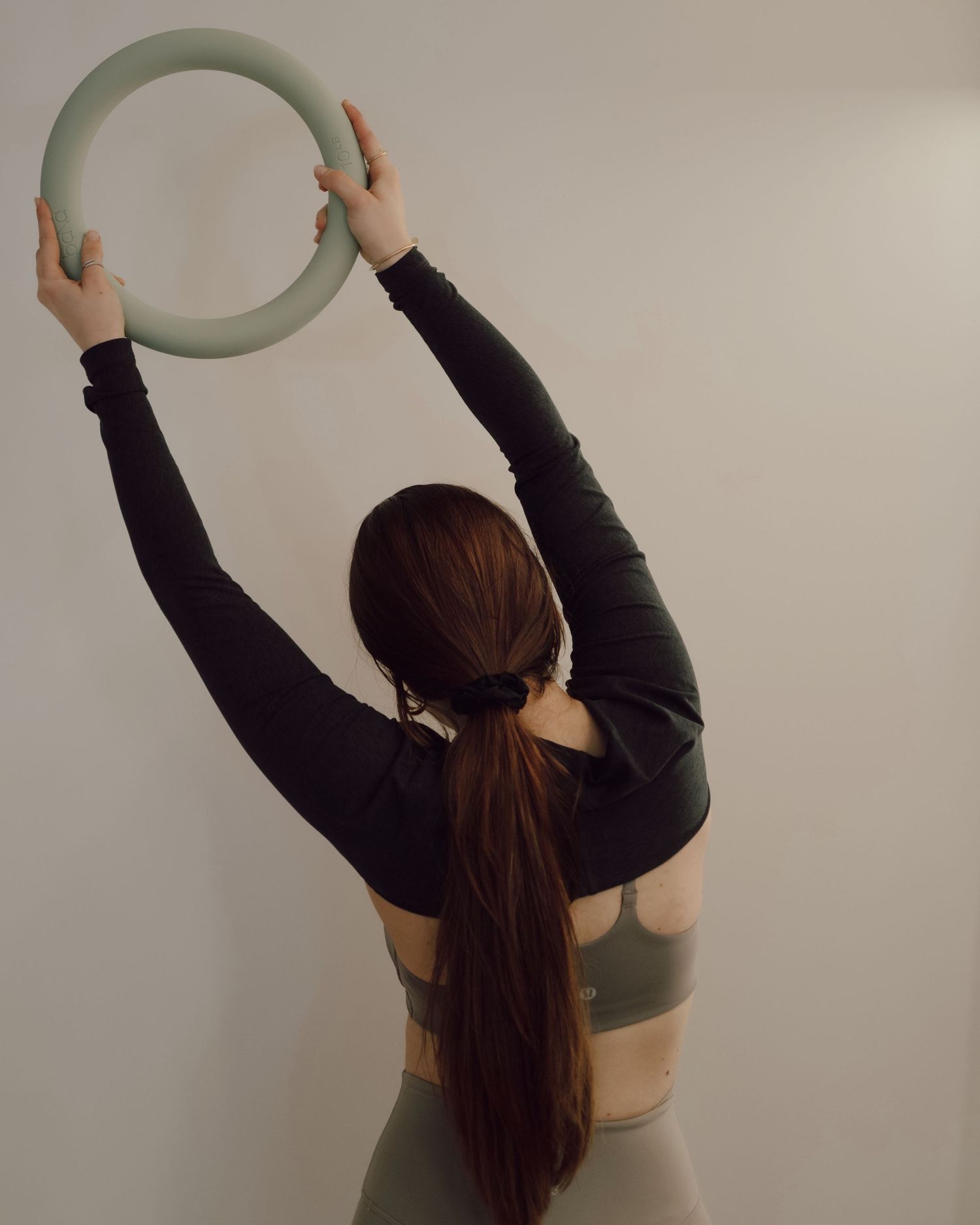 A person in a black top holds a green fitness resistance band overhead in a sequence of stretching poses.