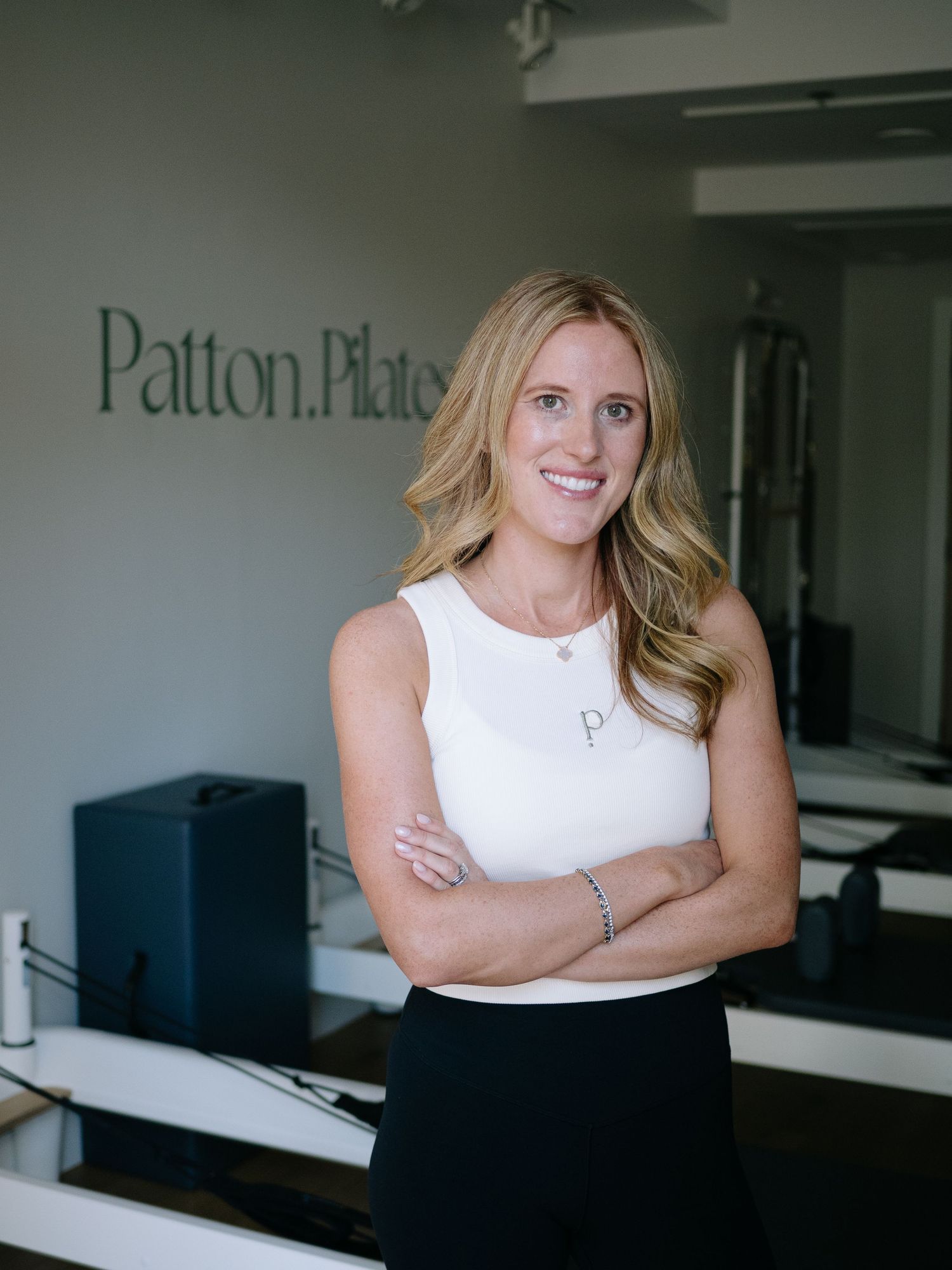 Professional headshot series of someone in a sleeveless white top against a modern office setting with clean lines and branding.