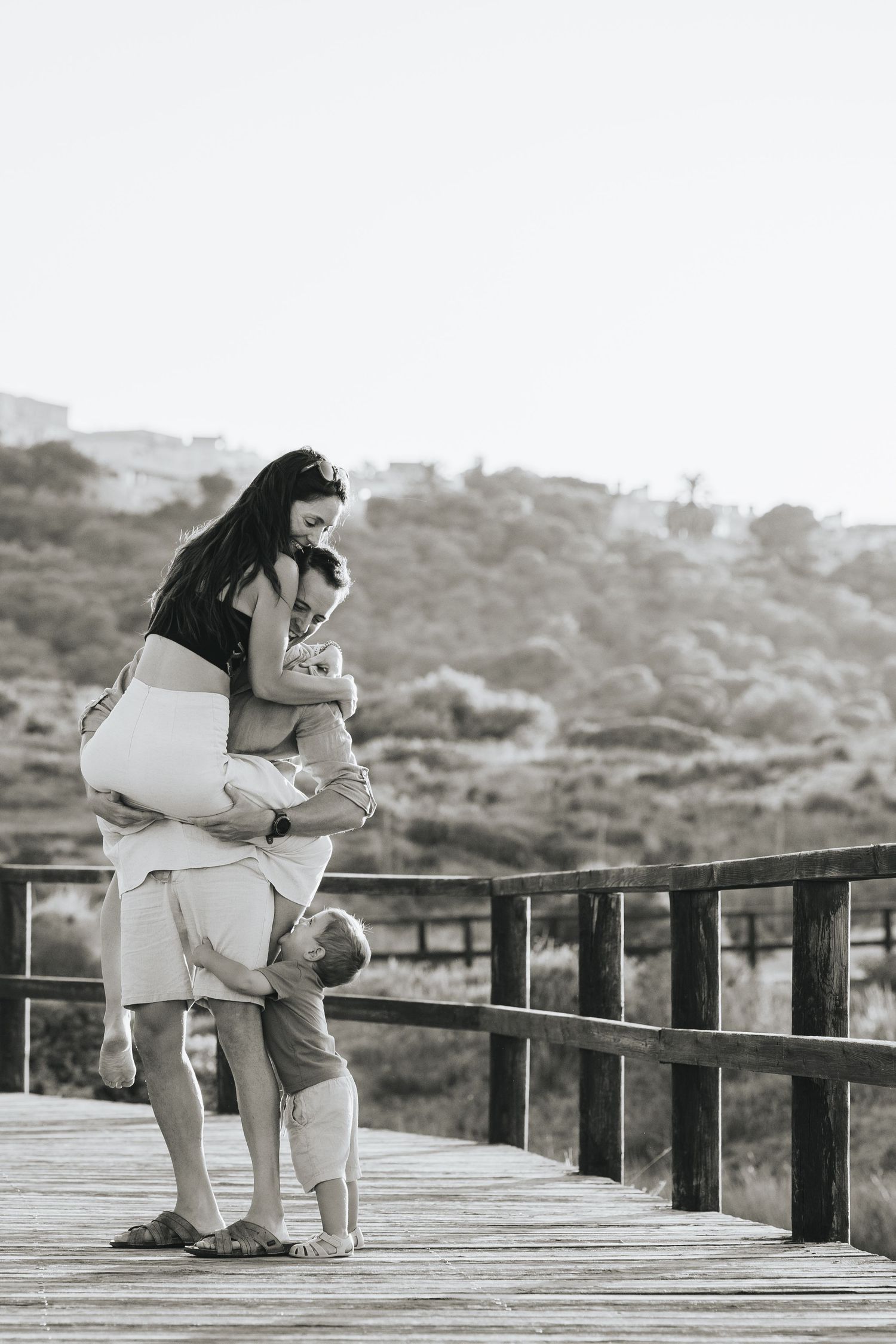 A couple embraces and laughs together in a sun-drenched outdoor setting with desert brush in the background.