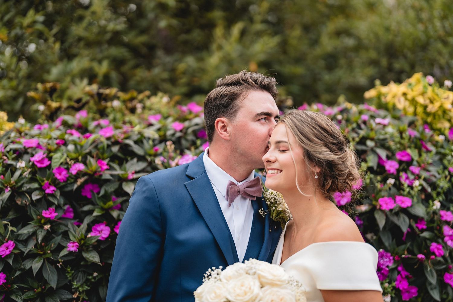 A romantic close up photo of a couple about to kiss at their wedding outdoors.