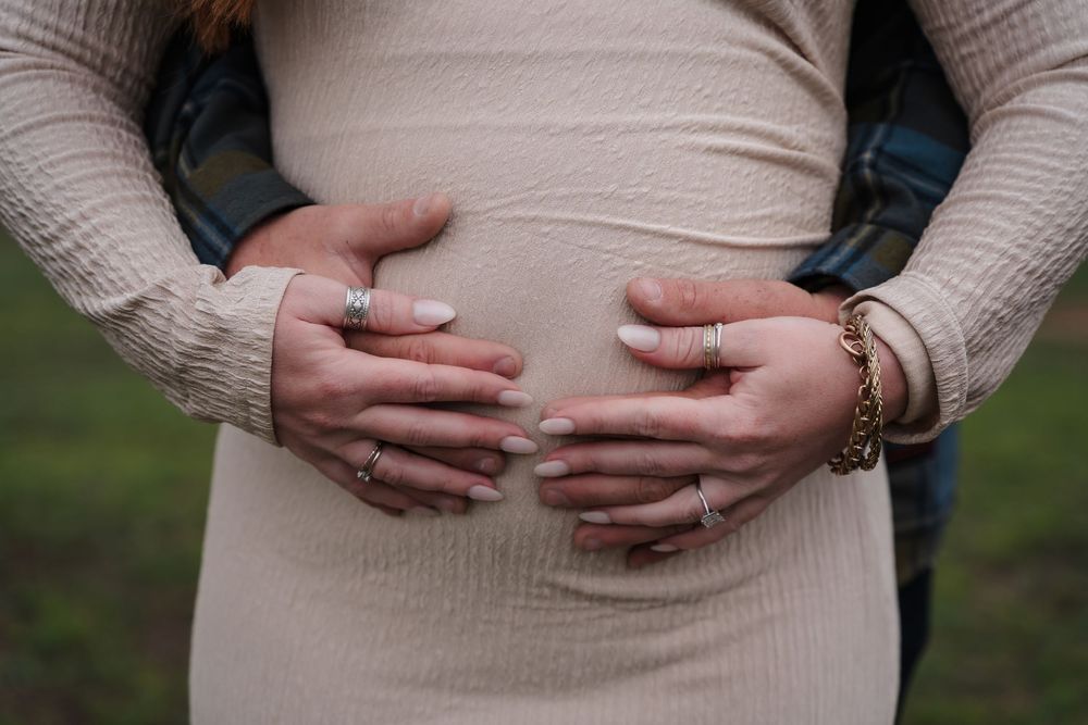 Close-up view of hands with wedding rings resting on a cream-colored sweater.