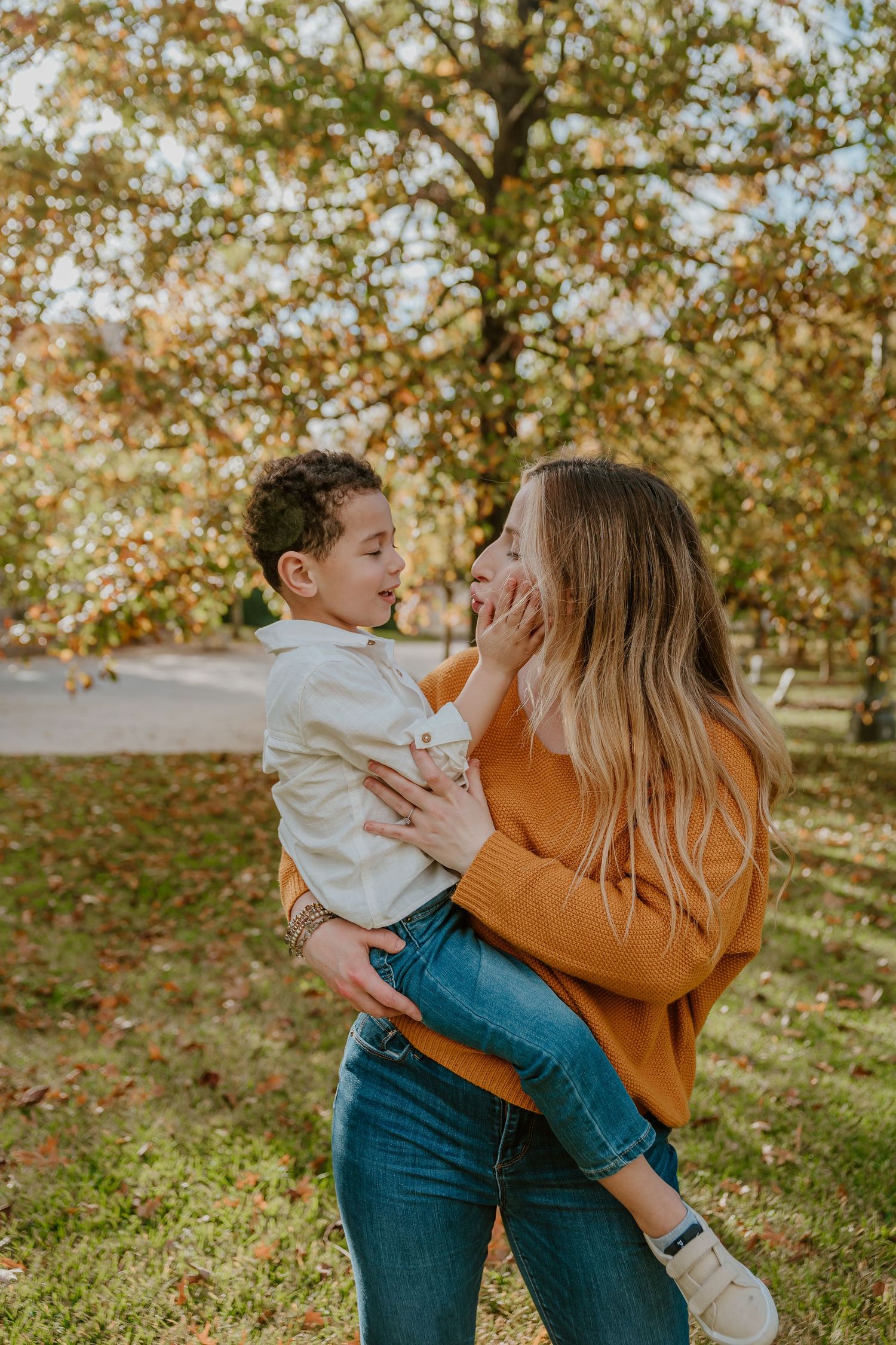 A touching autumn scene in a park showing a tender moment between a parent and child under golden leaves.