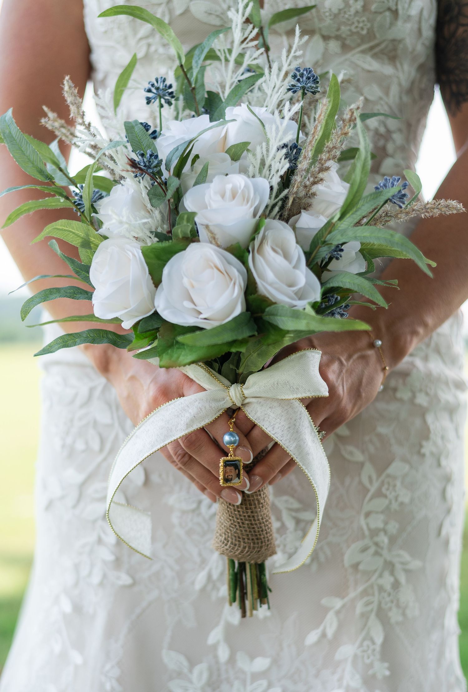 Elegant white rose bridal bouquet wrapped with burlap and ribbon featuring delicate blue accents and greenery.