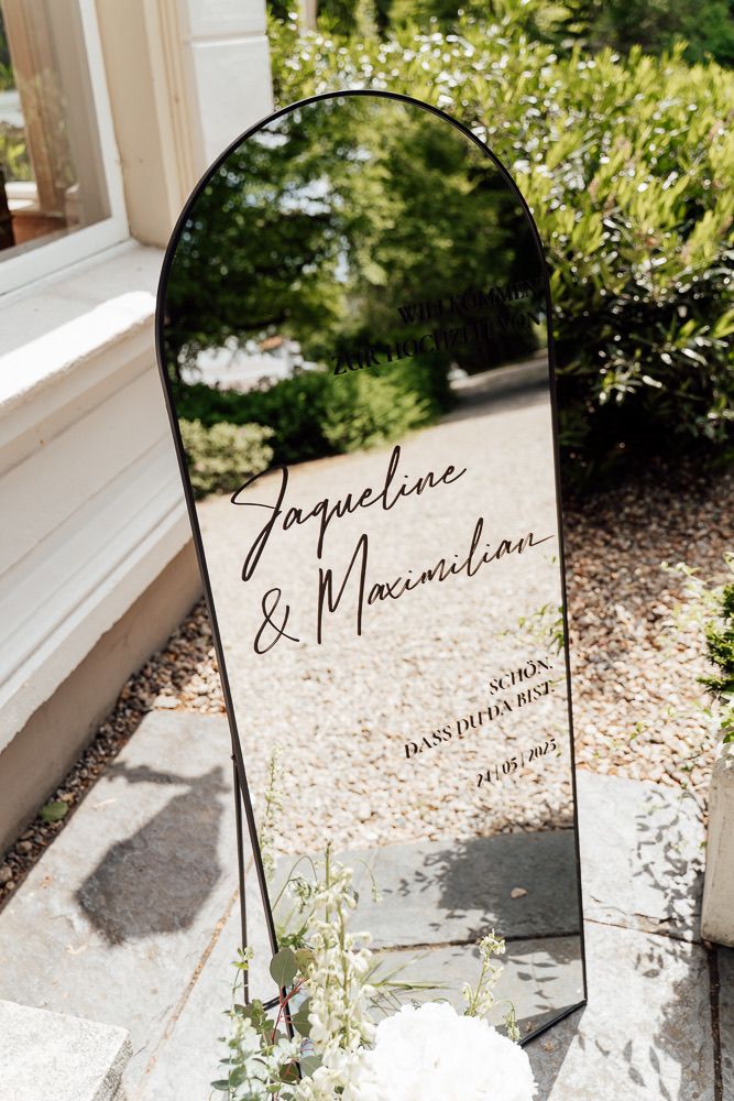Elegant handwritten calligraphy name cards displayed on white windowsills with soft natural lighting and greenery.