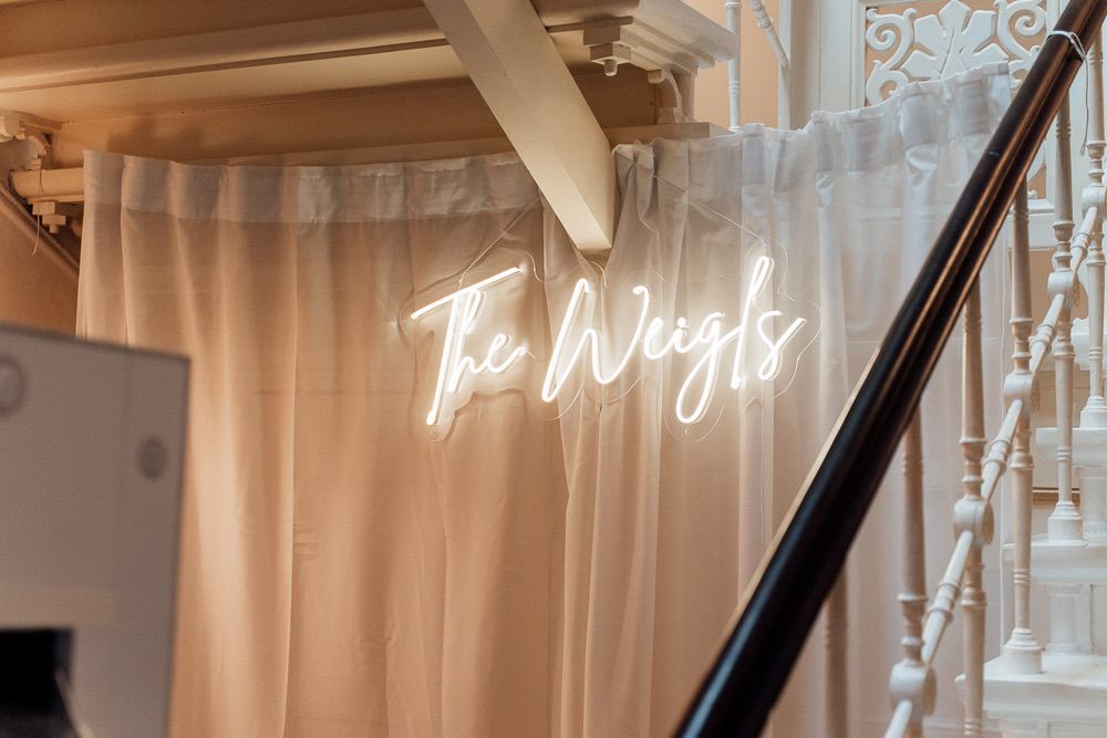A neon sign reading 'The Wright' glows against a light-colored wall in an interior setting.
