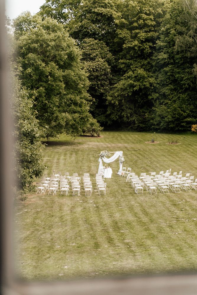 White chairs arranged in rows on a grassy lawn for an outdoor wedding ceremony.