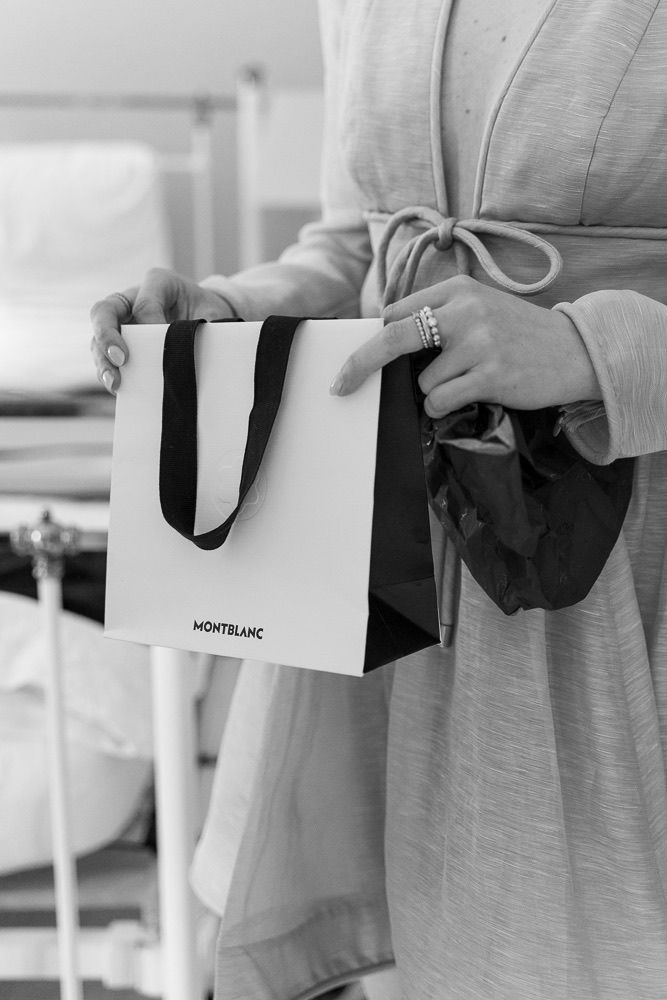 Row of hands holding Montblanc shopping bags in a black and white photograph.