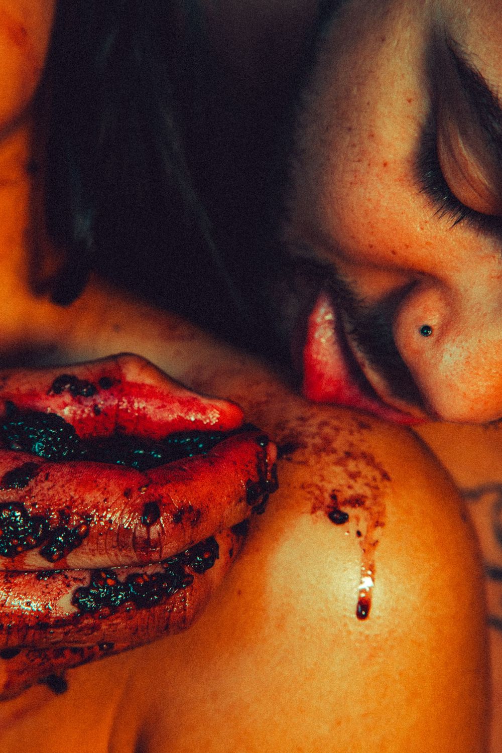 Close-up of a person with freckles eating a juicy slice of watermelon with dark seeds, juice dripping down.