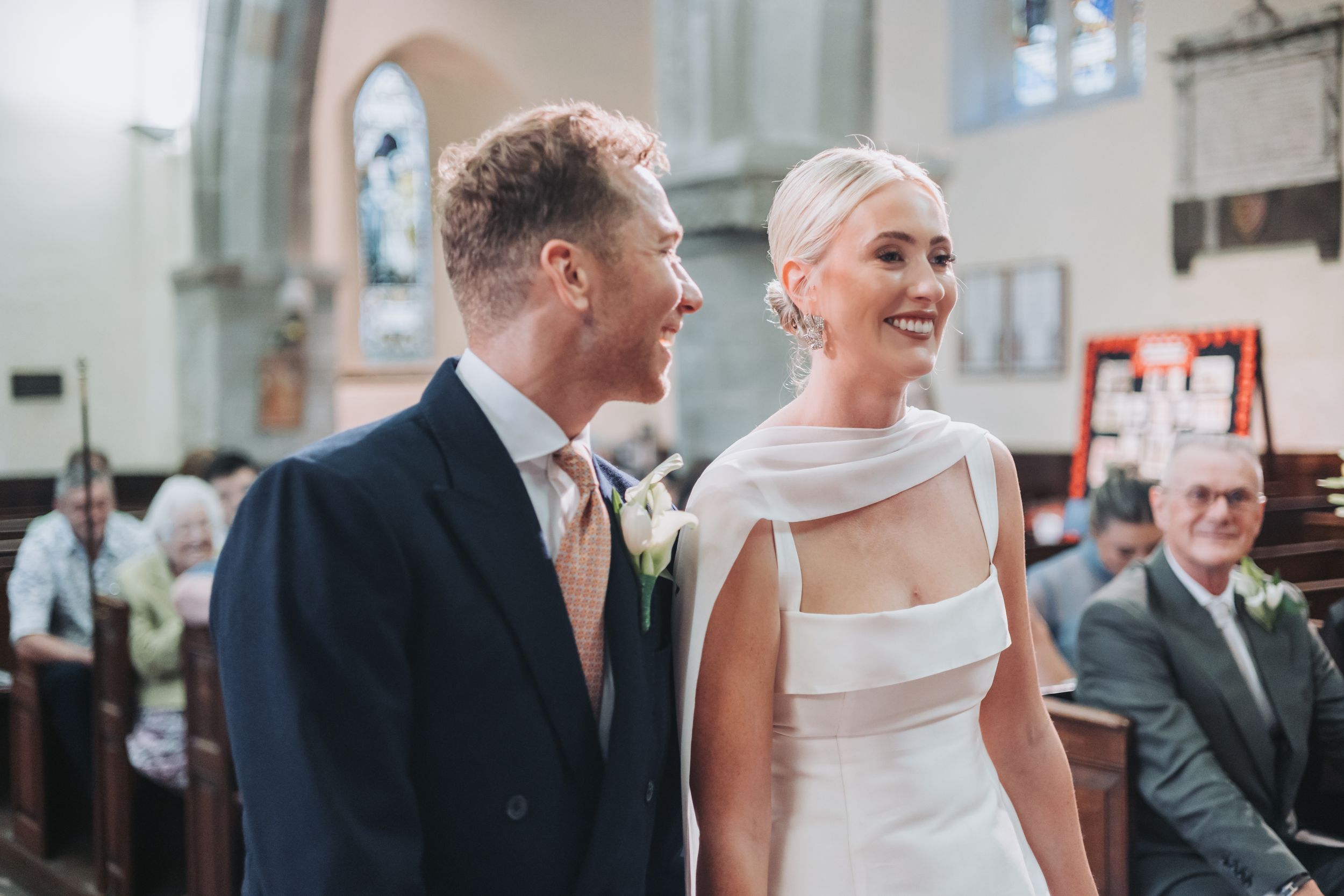 Smiling bride and groom share a joyful moment together at the church altar during their wedding.